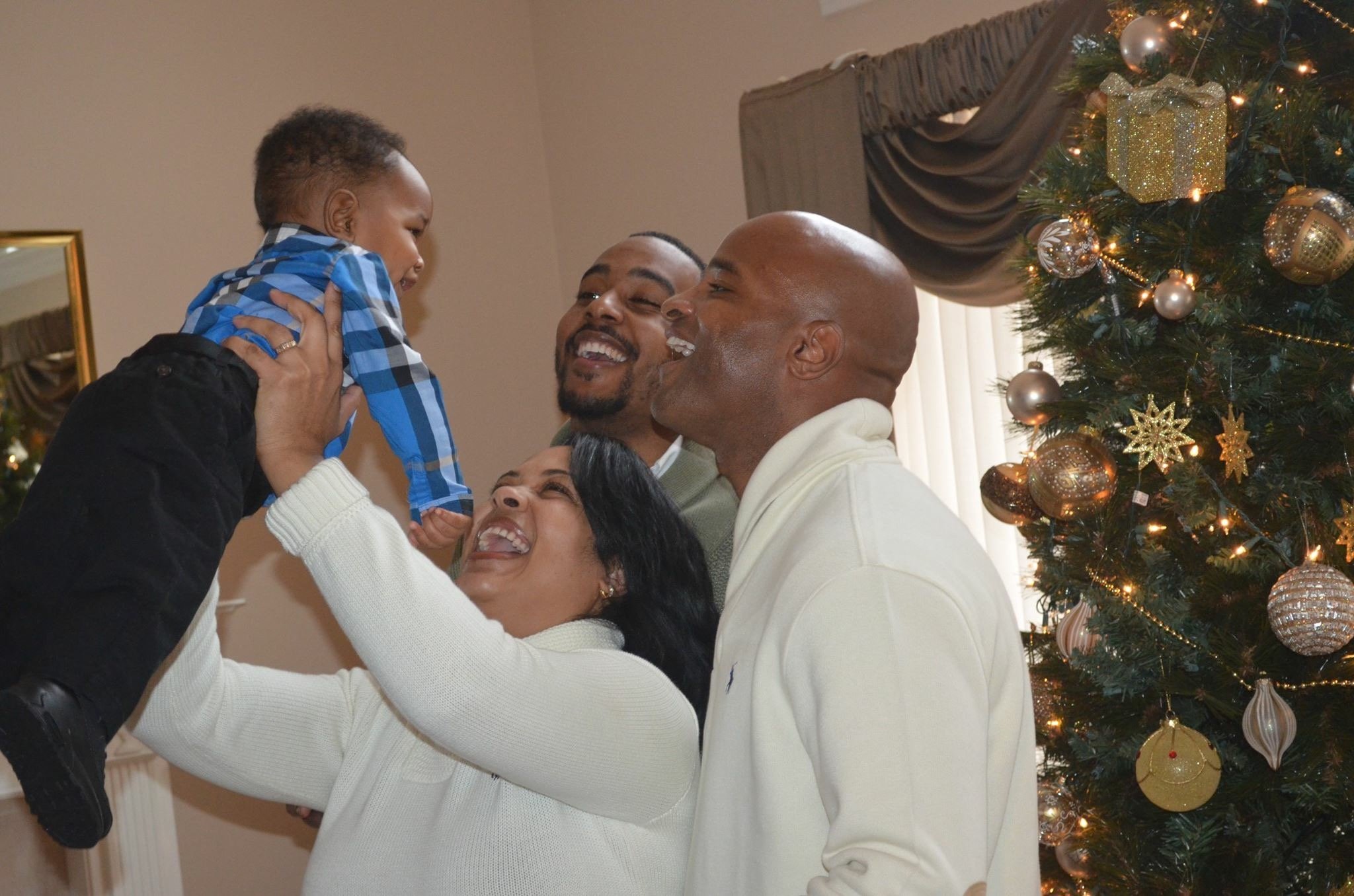 Charles with family smiling at baby lifted in the air.
