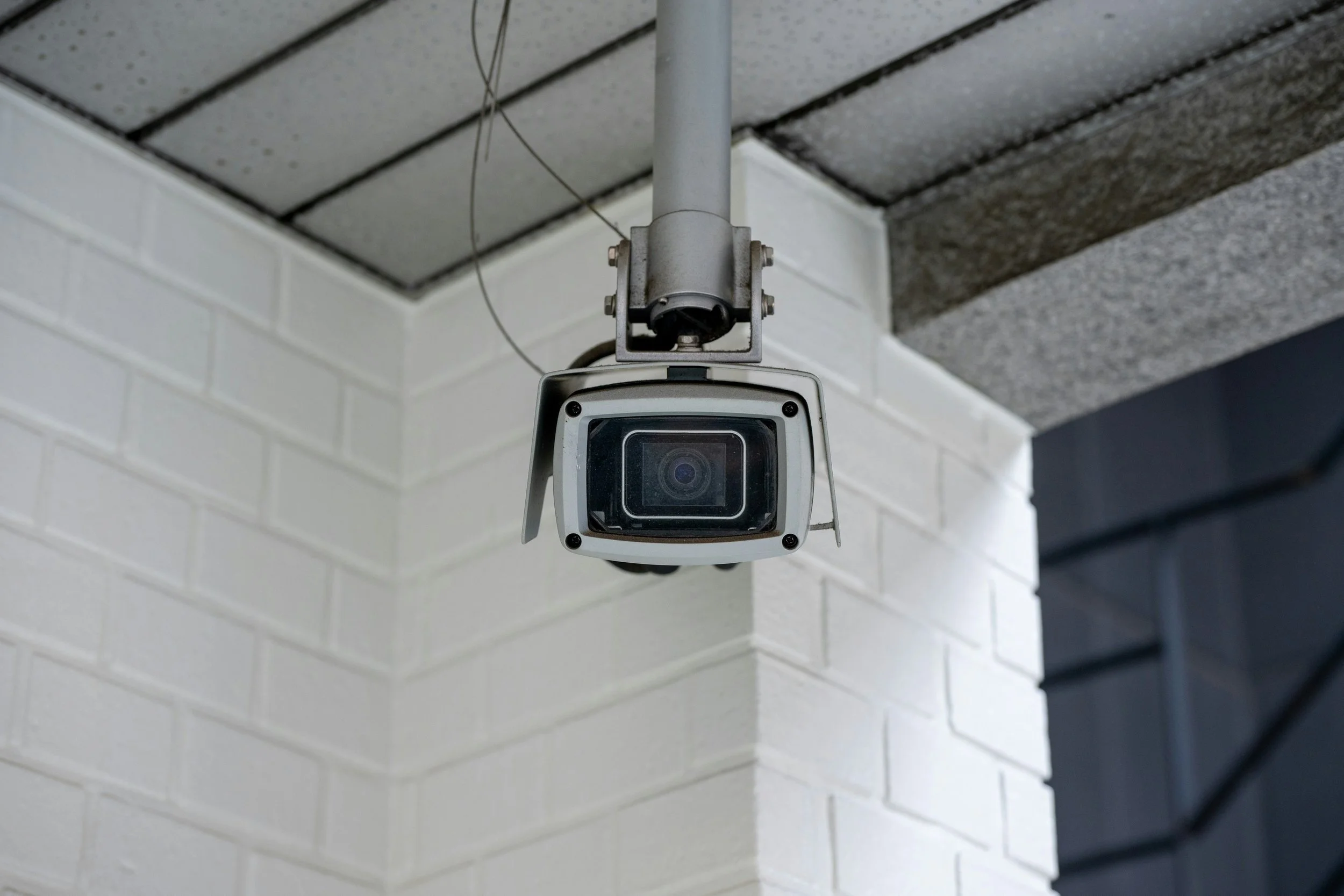 Security camera mounted on a ceiling, with a white brick wall in the background representing Seabrook Investigation Services, Essex based private investigators covert surveillance service