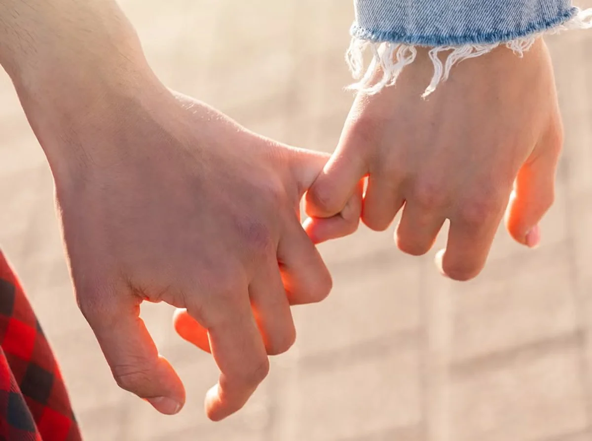 Two people are holding hands with their fingers intertwined.