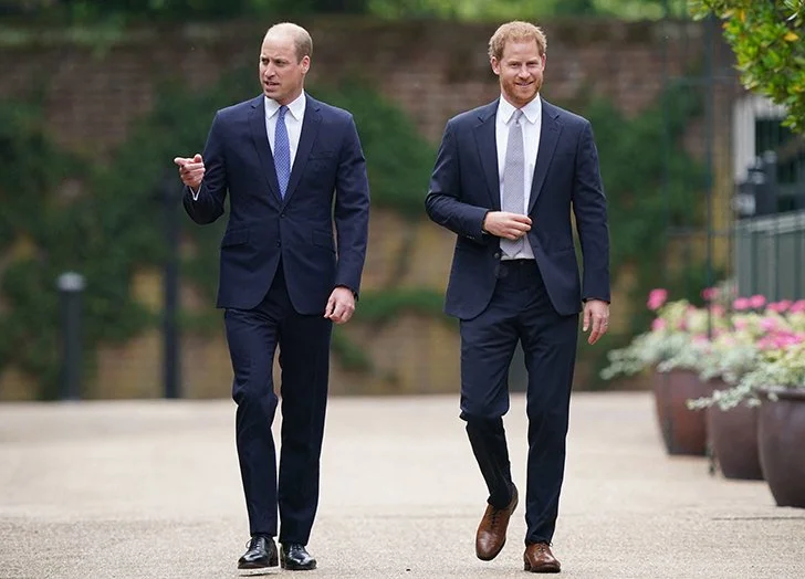 Two men in suits walking outdoors, engaging in conversation.