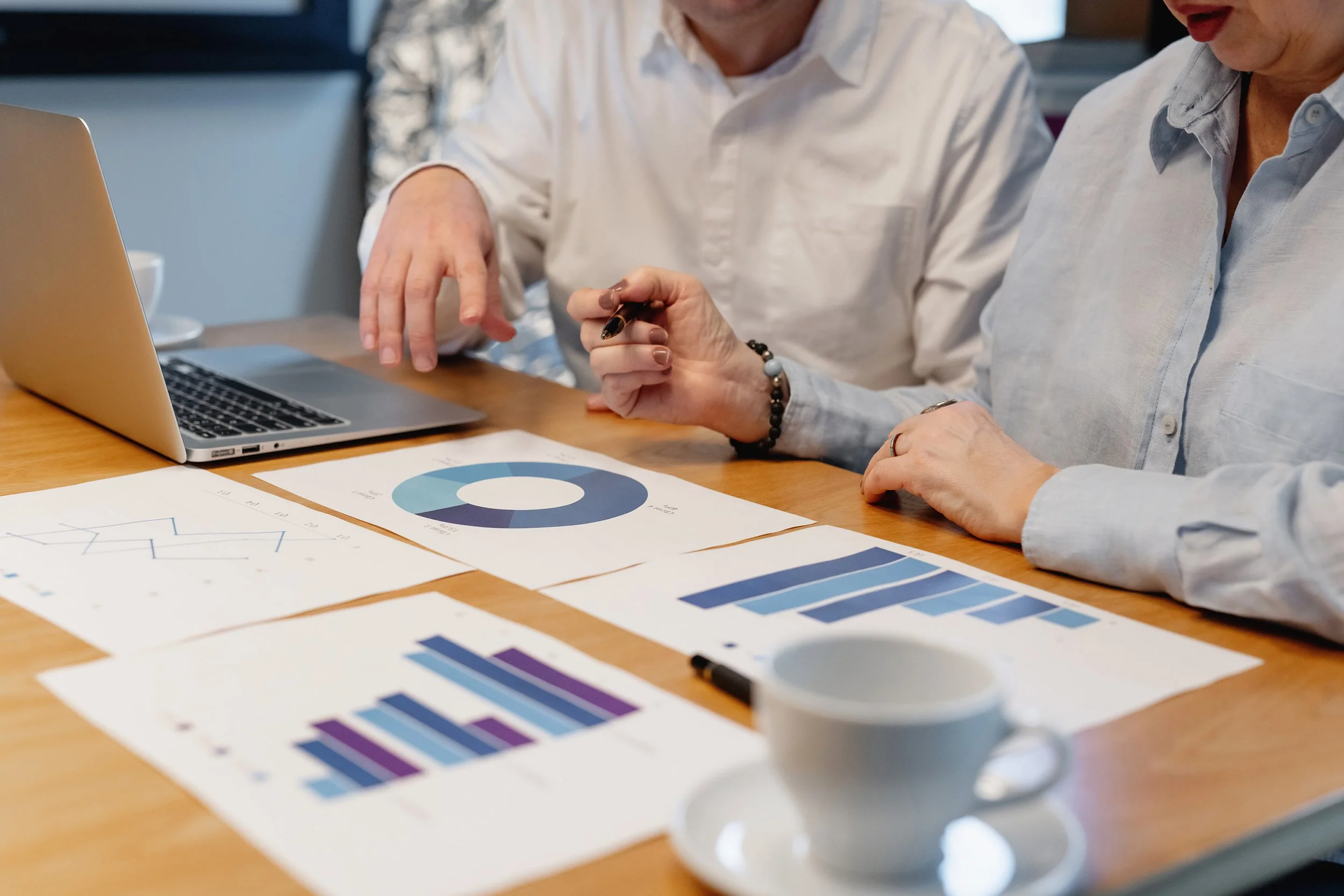 People working together at a table with charts and graphs, discussing data performance.