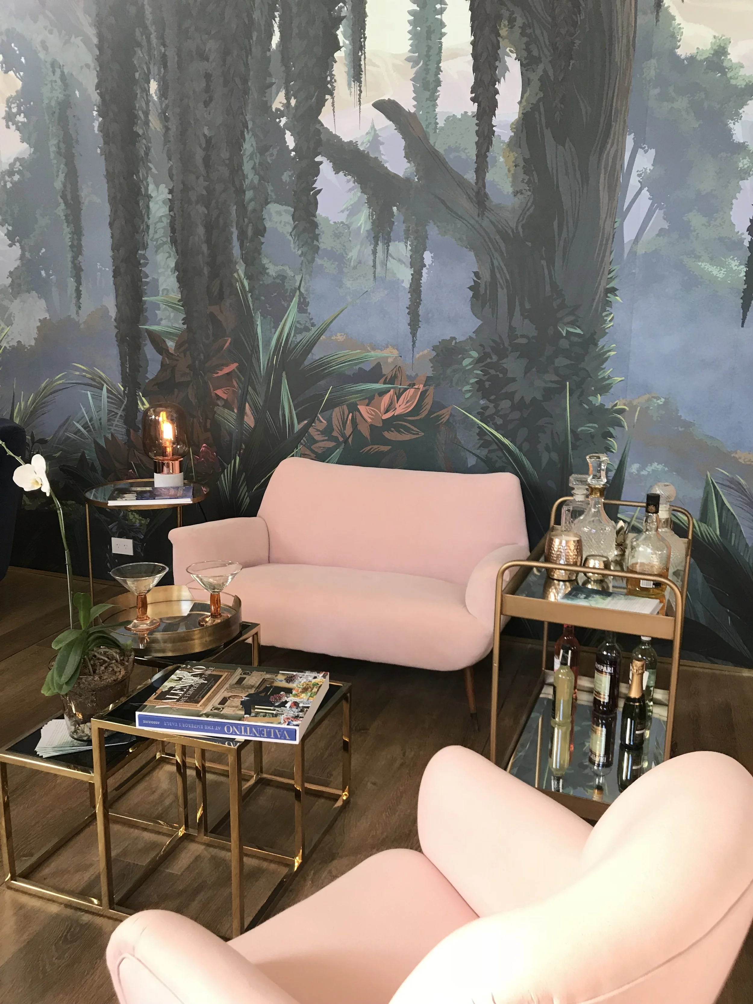 Biophilic luxury interior featuring lush botanical wall mural, curved velvet seating, and curated sustainable styling