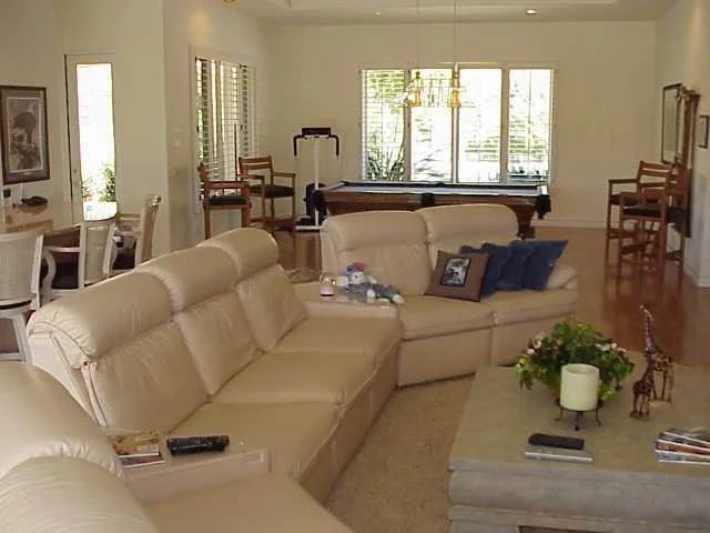 Living room with beige leather sofas, a large window, and various decorative items.