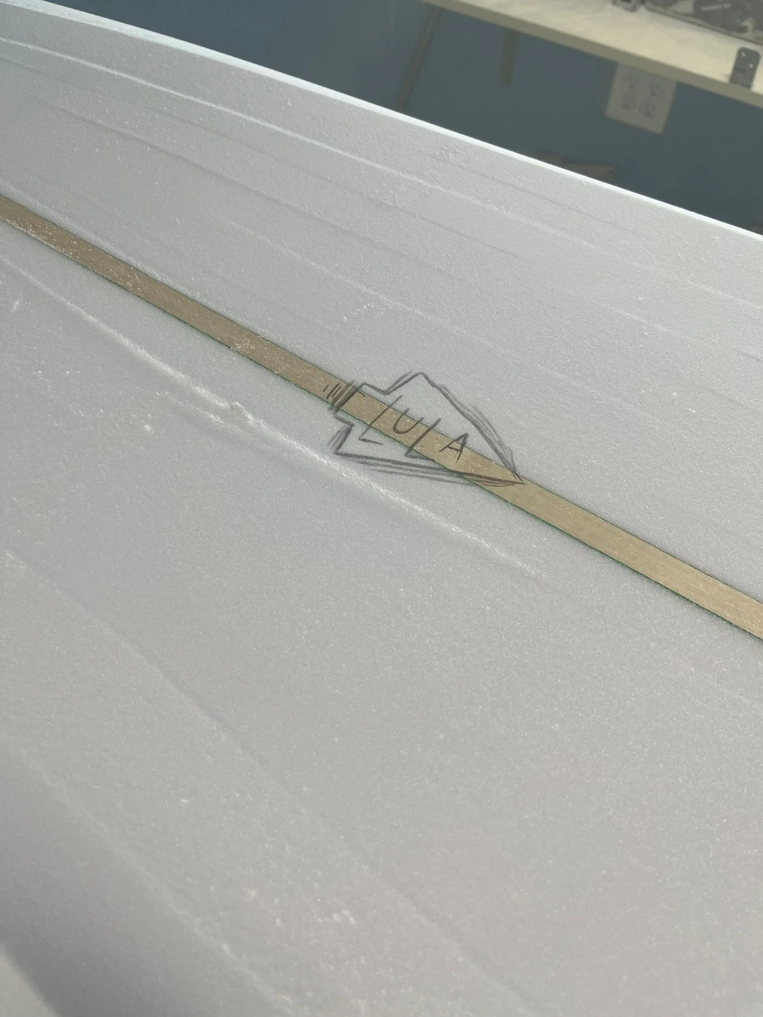 A close-up of a white foam or insulation material with a wooden stick labeled 'YUA' on it.