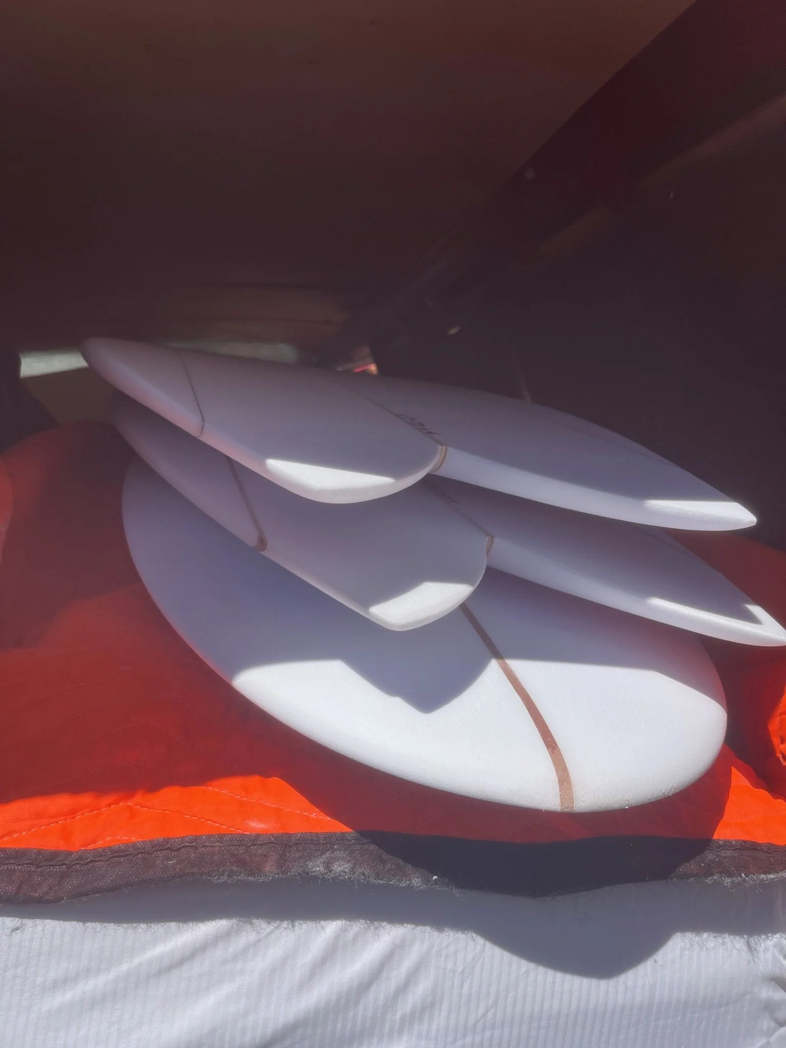 Array of white and red surfboards stacked together.