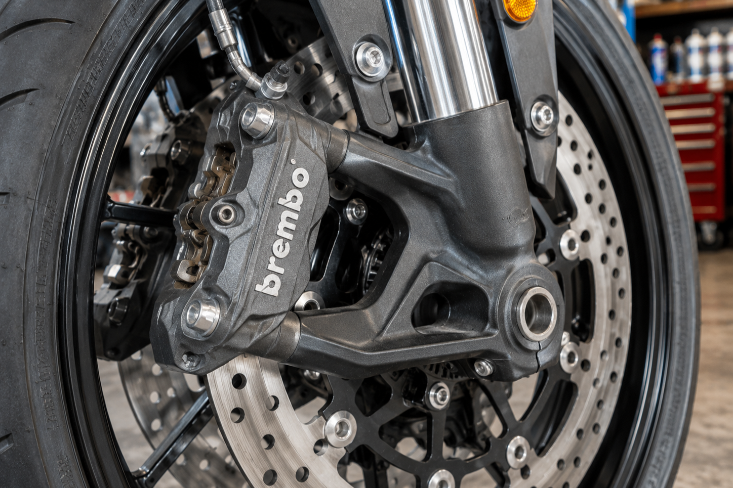 Close-up of a Brembo motorcycle brake caliper and disc brake on a bike wheel.