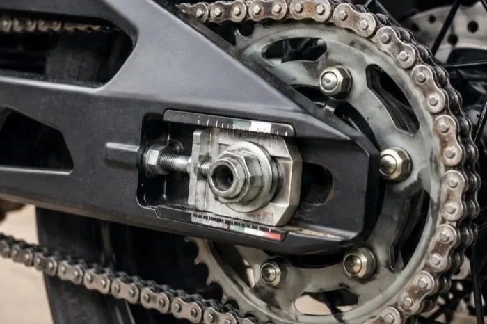 Close-up of motorcycle chain, sprocket, and rear wheel