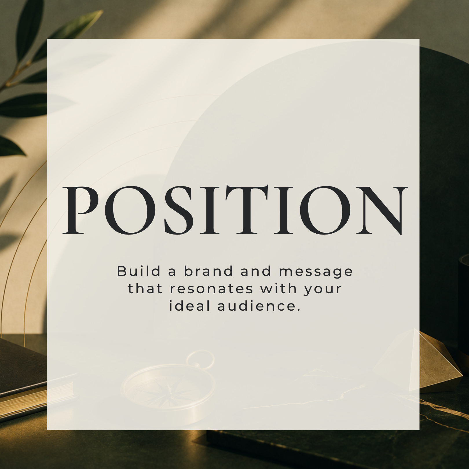 A close-up image of a white card with black text that reads 'POSITION Build a brand and message that resonates with your ideal audience,' placed on a dark surface with some decorative elements, such as a gold wire sculpture and leaves, partly visible in the background.