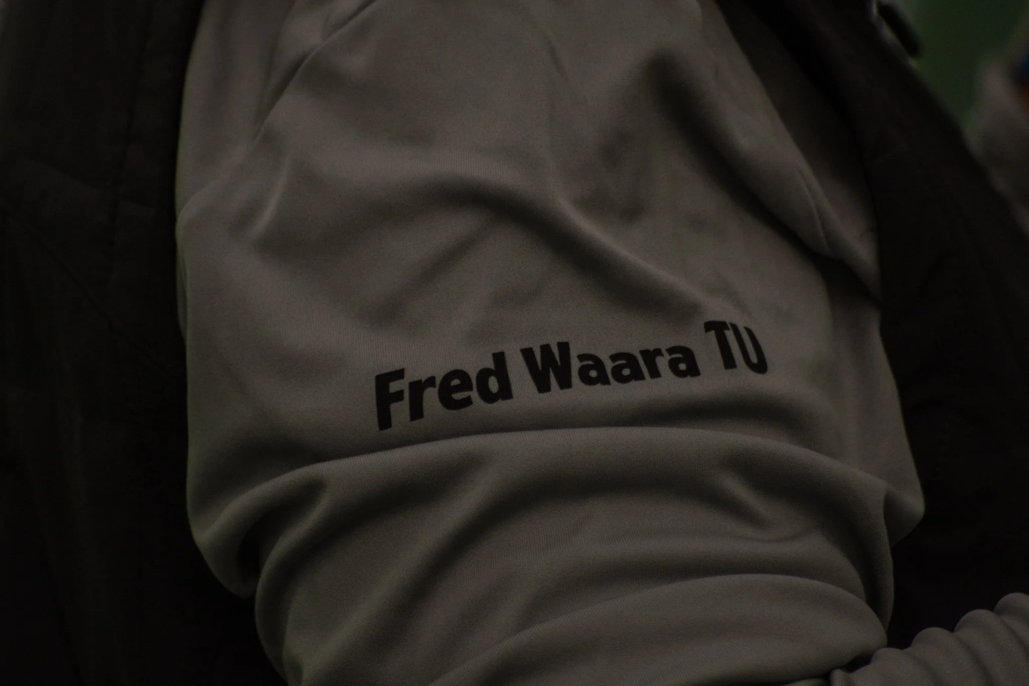 A person wearing a beige hoodie with the name "Fred Waara" printed on it in black letters.