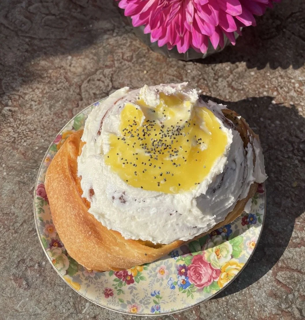 A lemon poppyseed cinnamon bun on a floral plate.