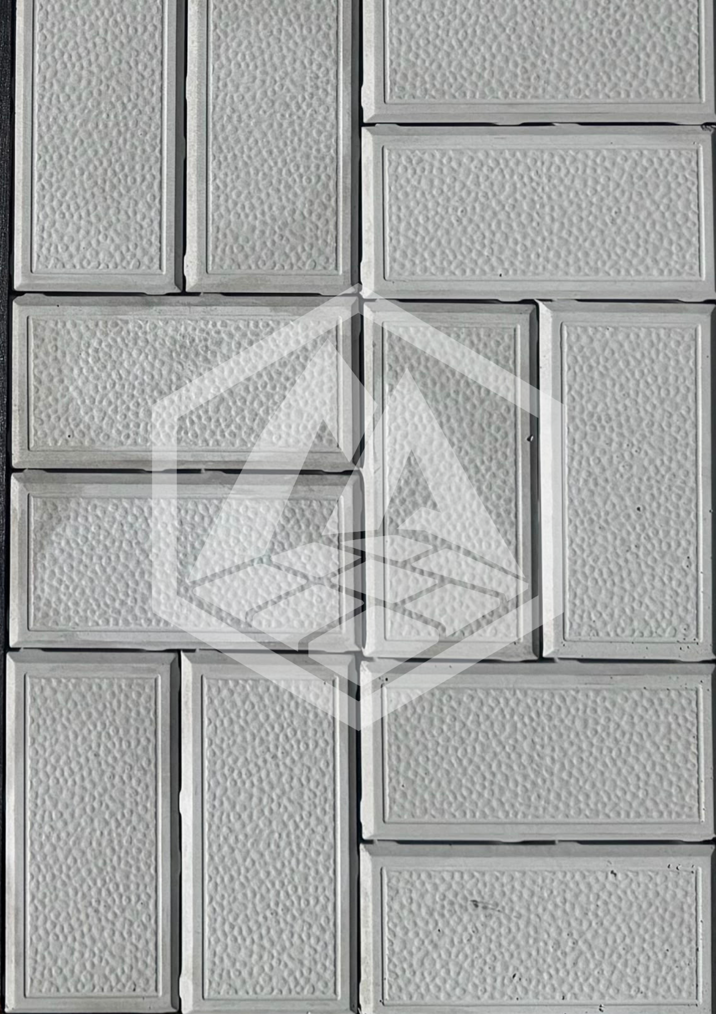 Close-up of a wall made of rectangular white textured tiles with a raised pattern, arranged in a grid.