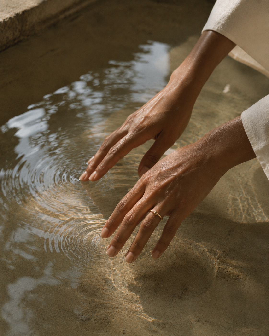 Hands touching water — stillness and presence