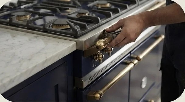 Close-up of a person's hand turning on the oven stove with a marble countertop in the background.