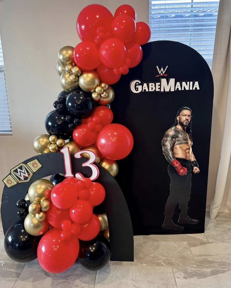 WWE-themed birthday display with red, black, and gold balloons & Roman Reigns cutout to celebrate "GabeMania"
