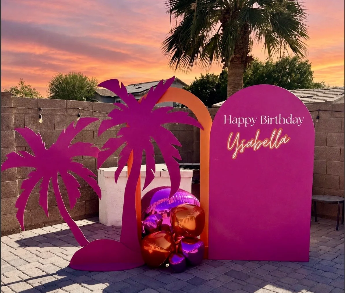 Tropical Orange and Pink birthday celebration at sunset featuring palm tree props and an open arch backdrop