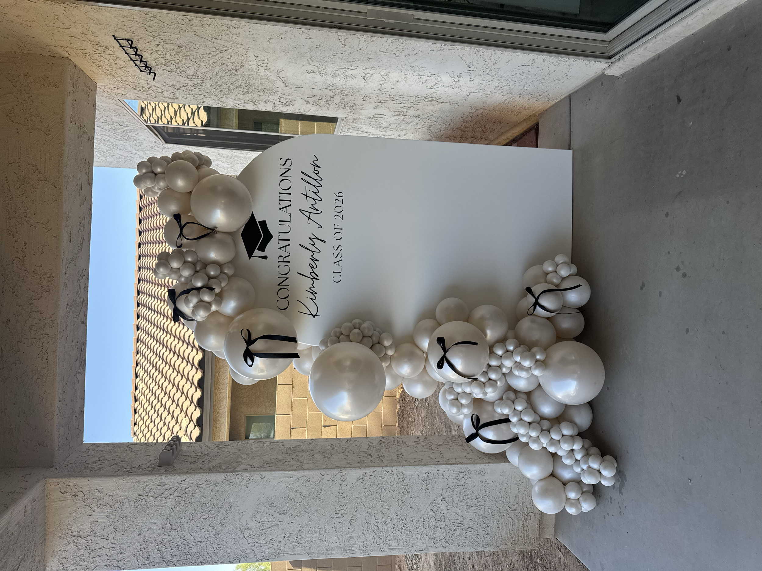 Ivory pearl balloons with black bow accents for an elegant graduation party celebration