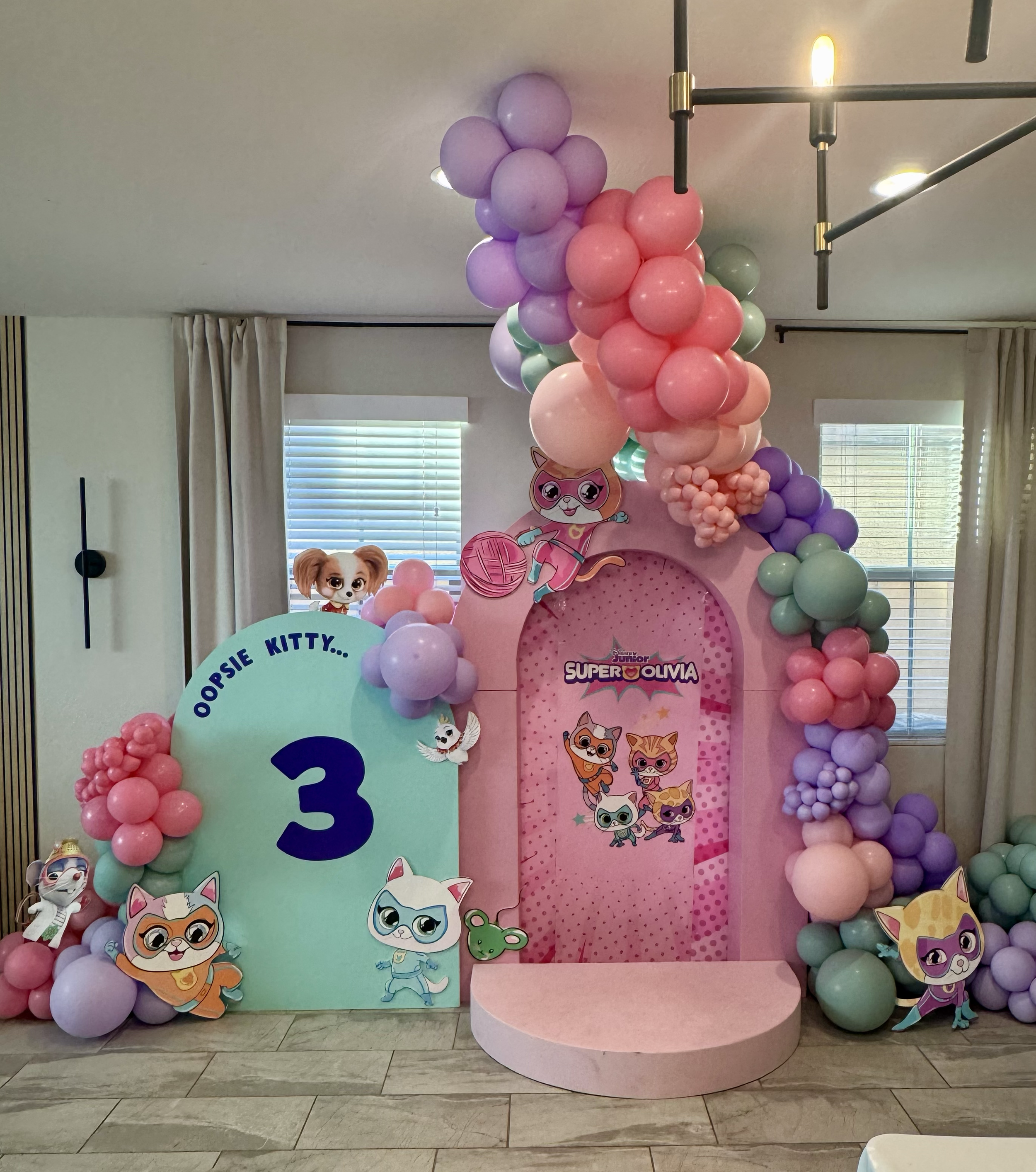 "Super Olivia" perfect birthday setup for the kitty cat-loving toddler! Featuring Disney SuperKitties character cutouts, pastel balloon colors, a 3D backdrop, elevated stage, & ceiling balloon installation