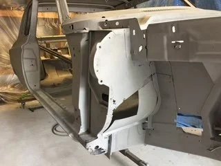 A partially assembled vehicle body on a workshop frame.