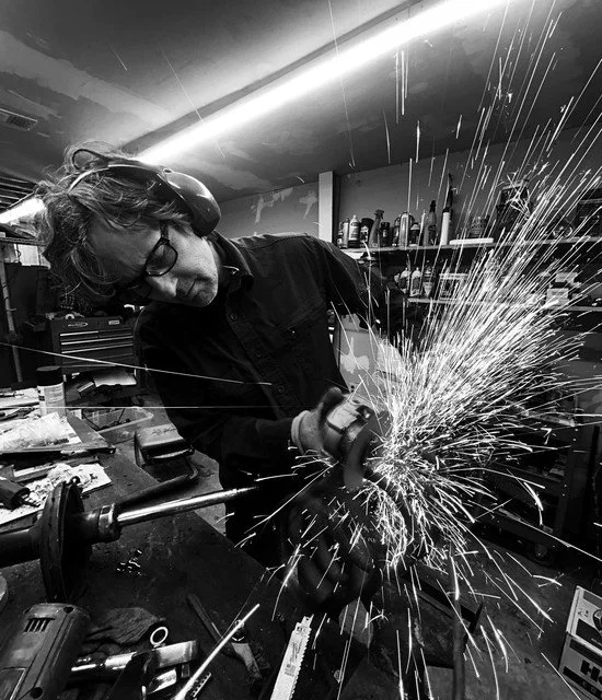 Person grinding metal in a workshop with sparks flying.