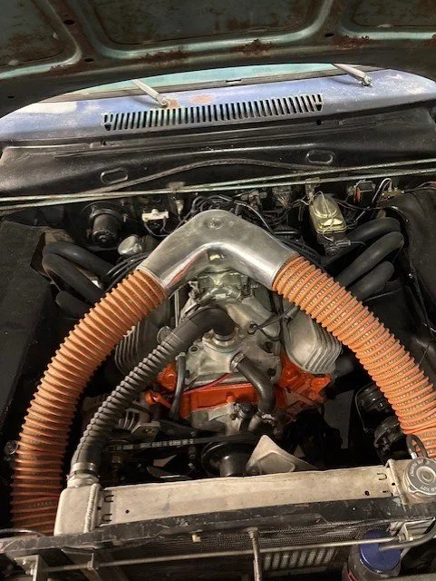 View of a car engine with orange hoses and a large metal air intake.