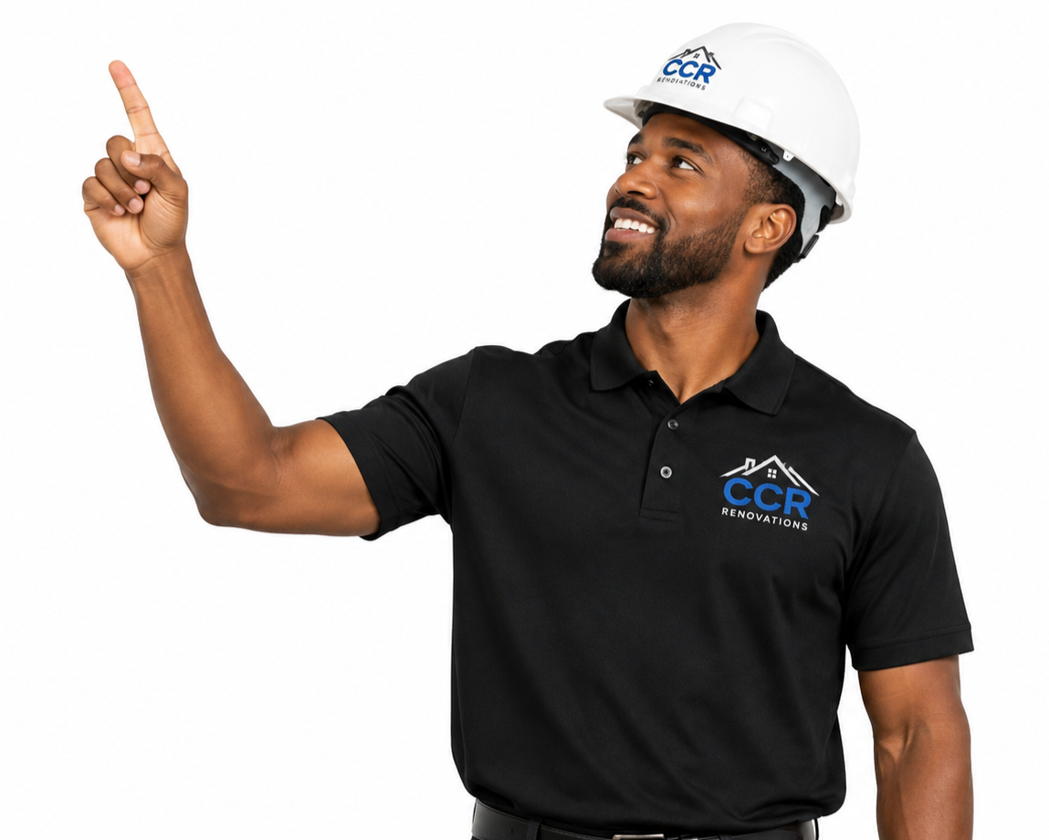 A man wearing a white safety helmet and a black polo shirt with a CCR Renovations logo, pointing upward with his right index finger, smiling, and looking slightly to his left.