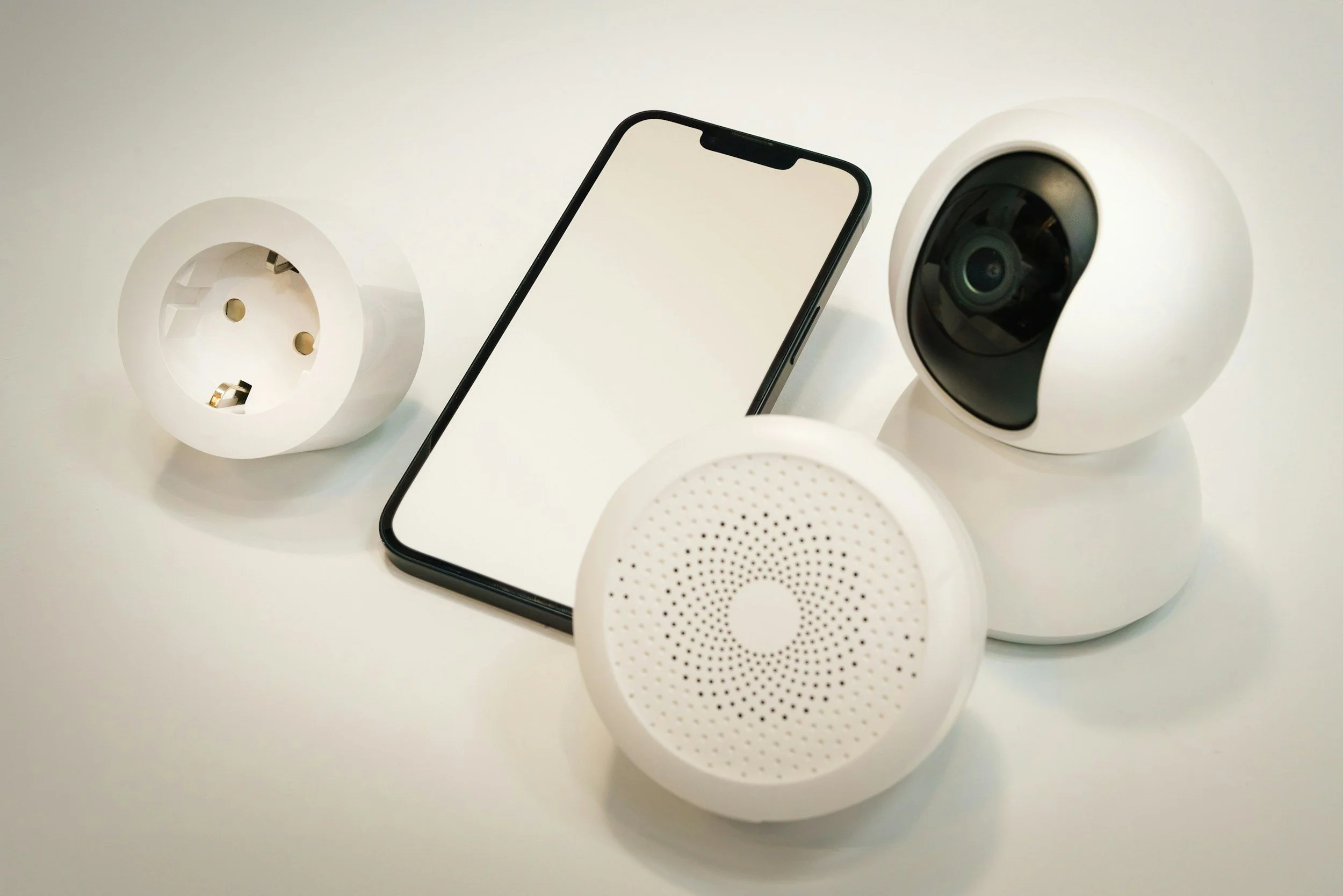 A collection of modern security cameras and a smartphone displayed on a white surface.