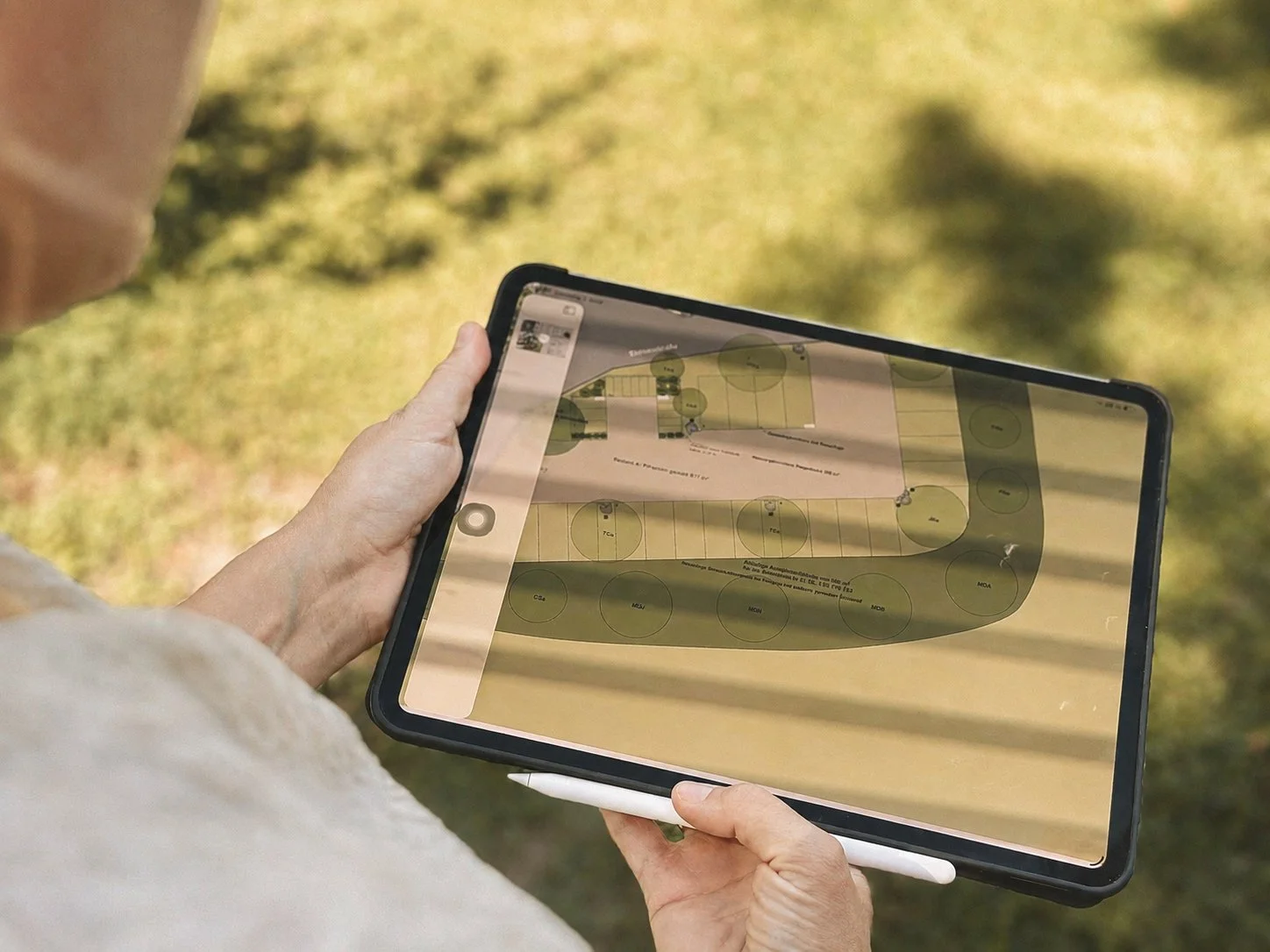 Person hält ein Tablet mit einem Plan oder Diagramm im Freien.