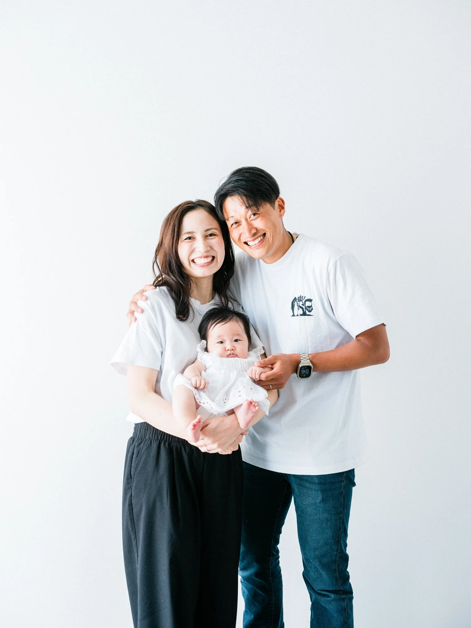 お揃いの白いTシャツのご夫婦。100日祝いのお子さんとの家族写真。