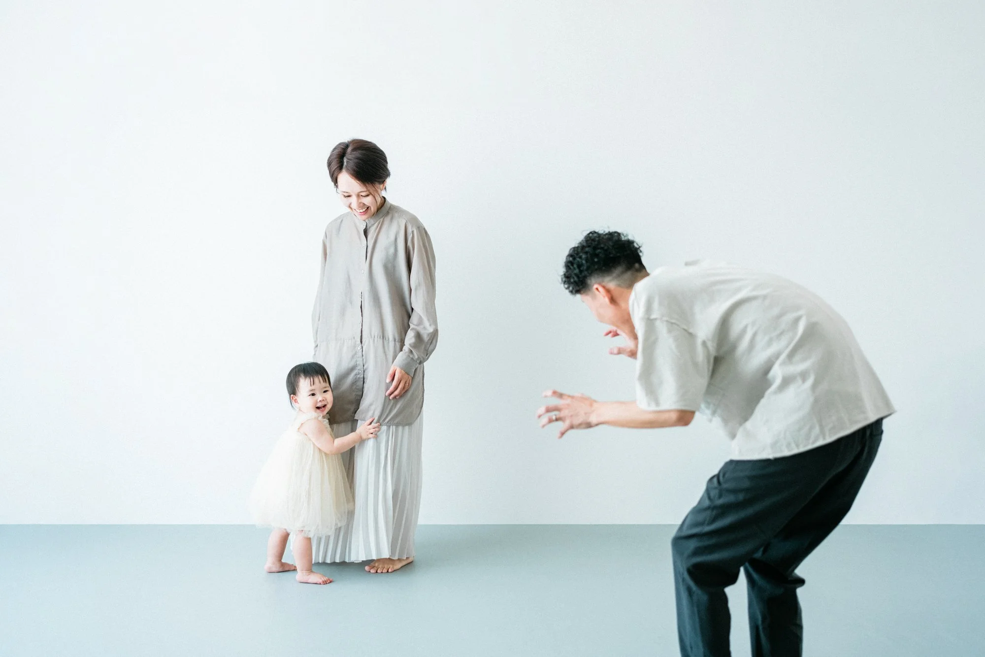 家族が笑顔で写真を撮っているシーン。お母さんと女の子をお父さんが笑わかせているところ。