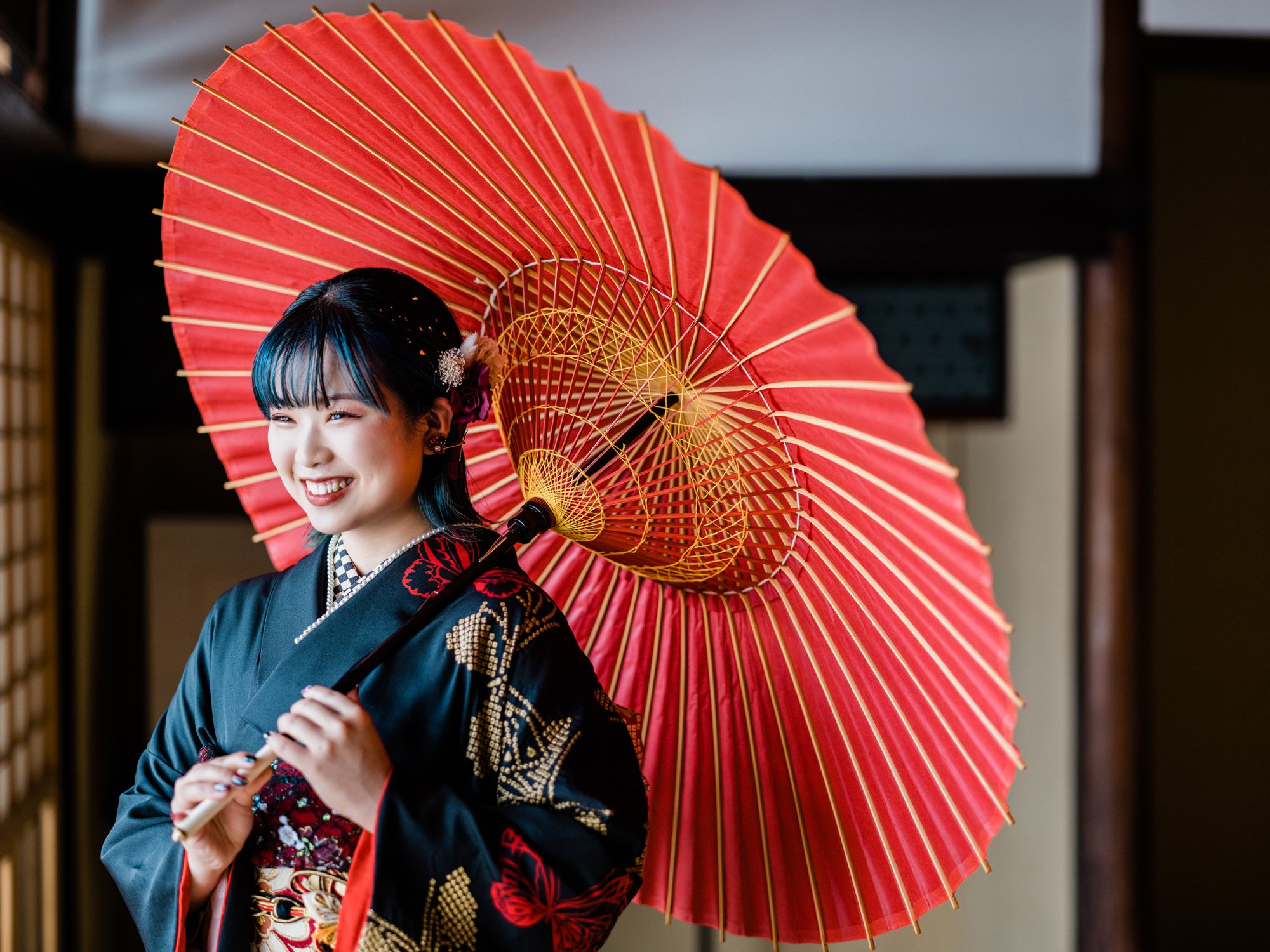 振袖を着た女性が和傘を持ち、笑顔で振り向いている。ナチュラルな成人式の前撮り。
