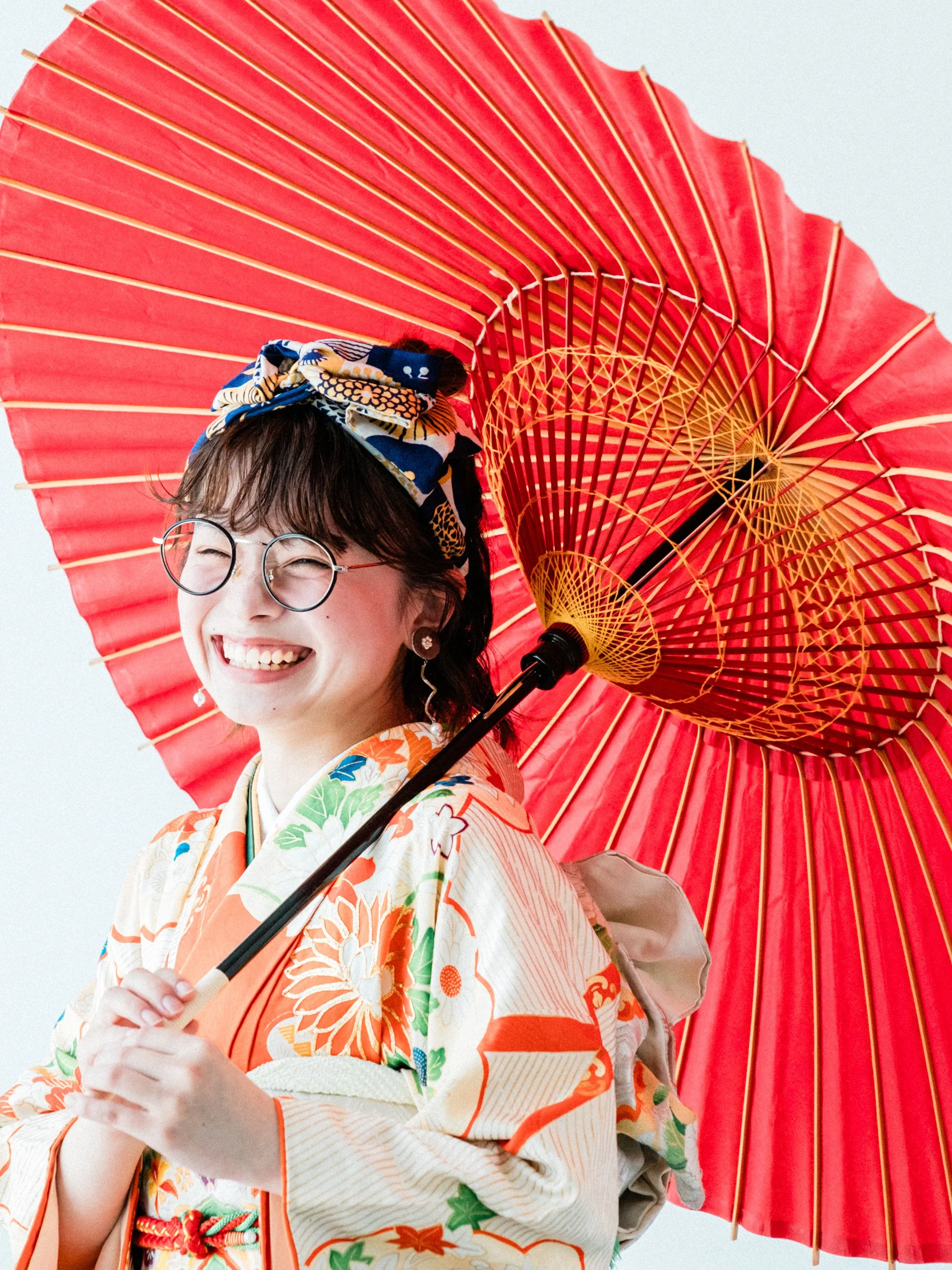 笑顔の女性が振袖を着ていて、赤い和傘を持っている写真。成人式の前撮り。