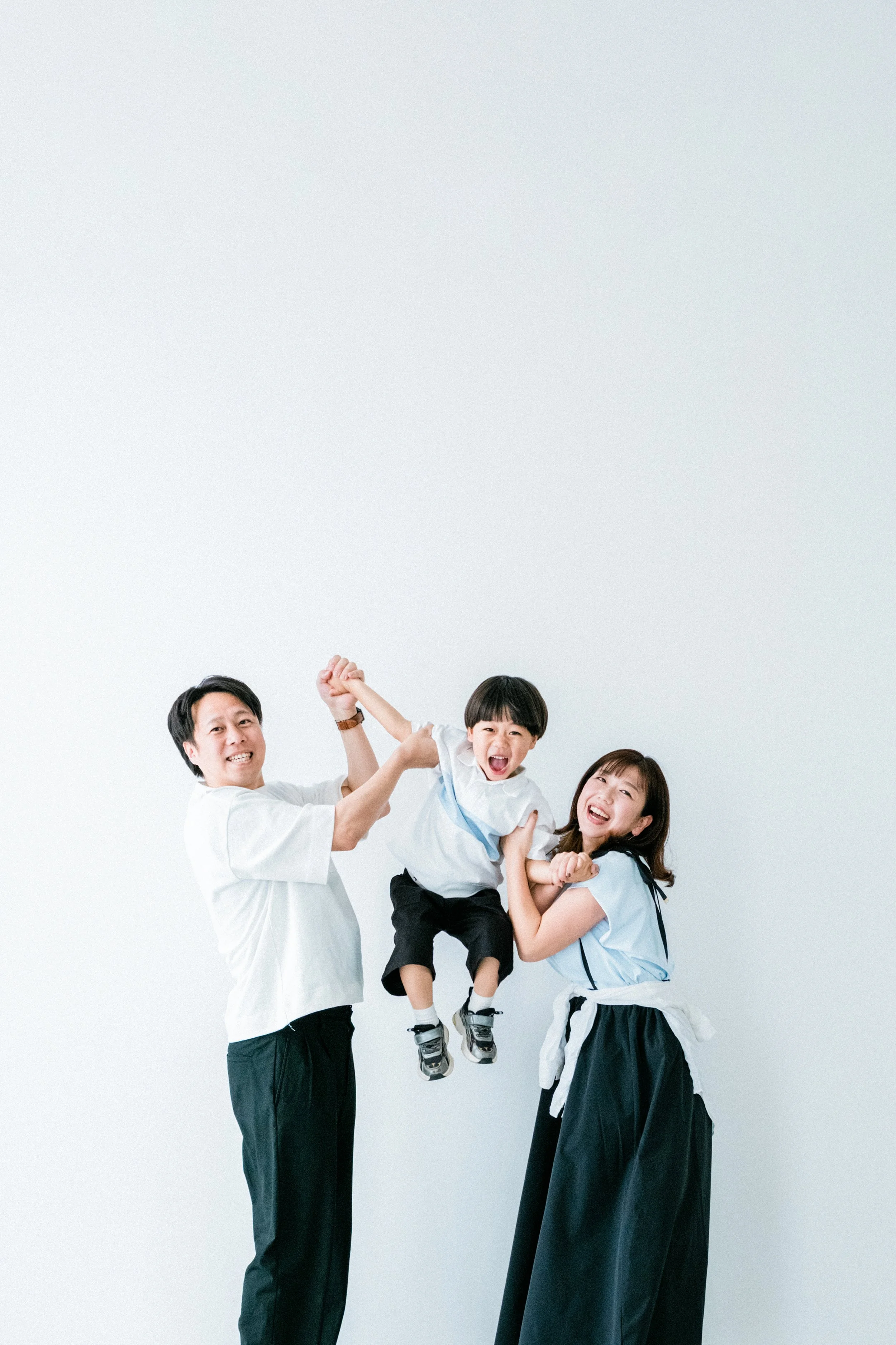 家族が笑顔でポーズをとり、子供を中心にして喜びを表現している。自然体な家族写真。