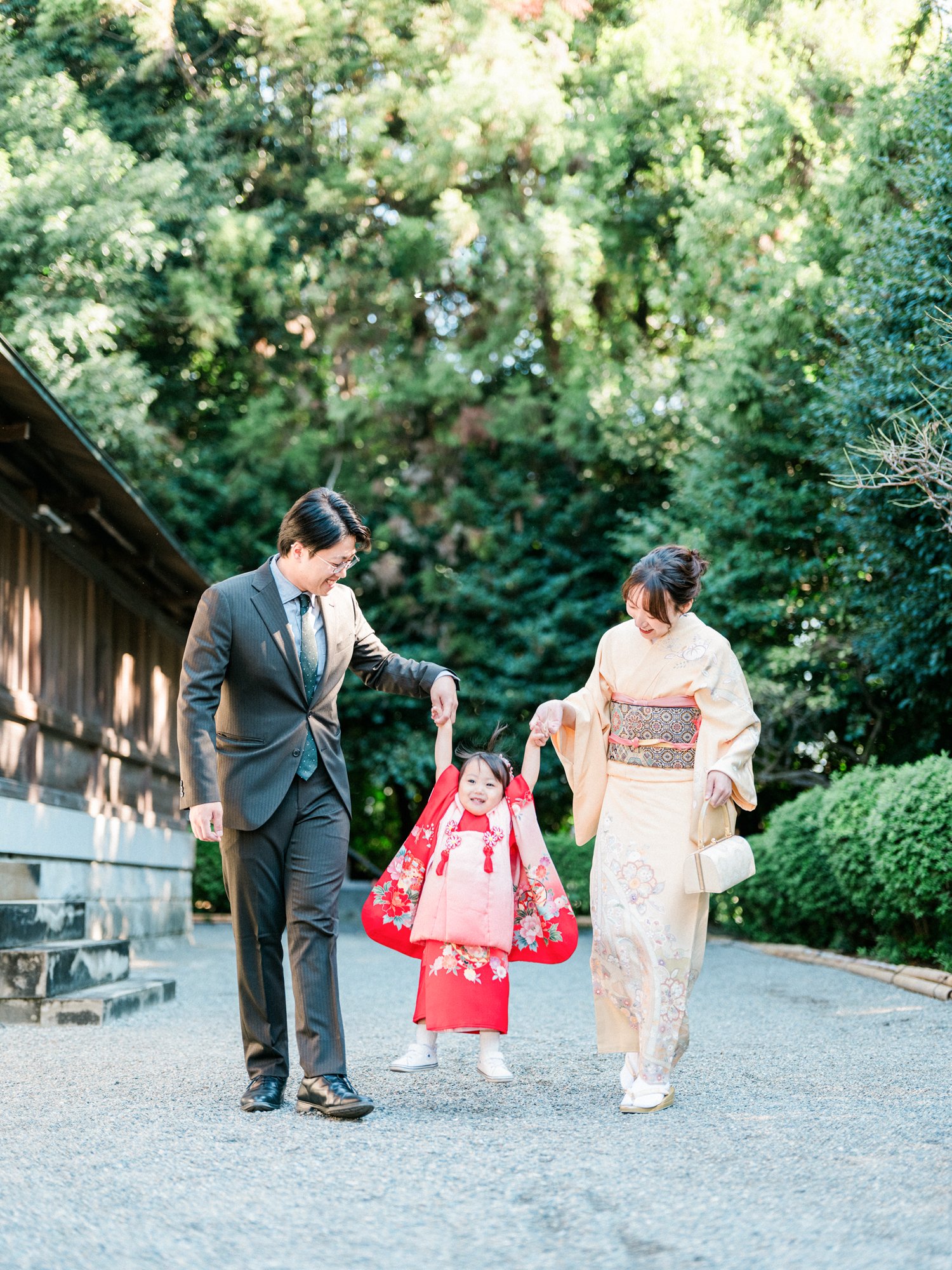 家族が神社で和服とスーツを着て歩いている写真。出張の七五三の前撮り。