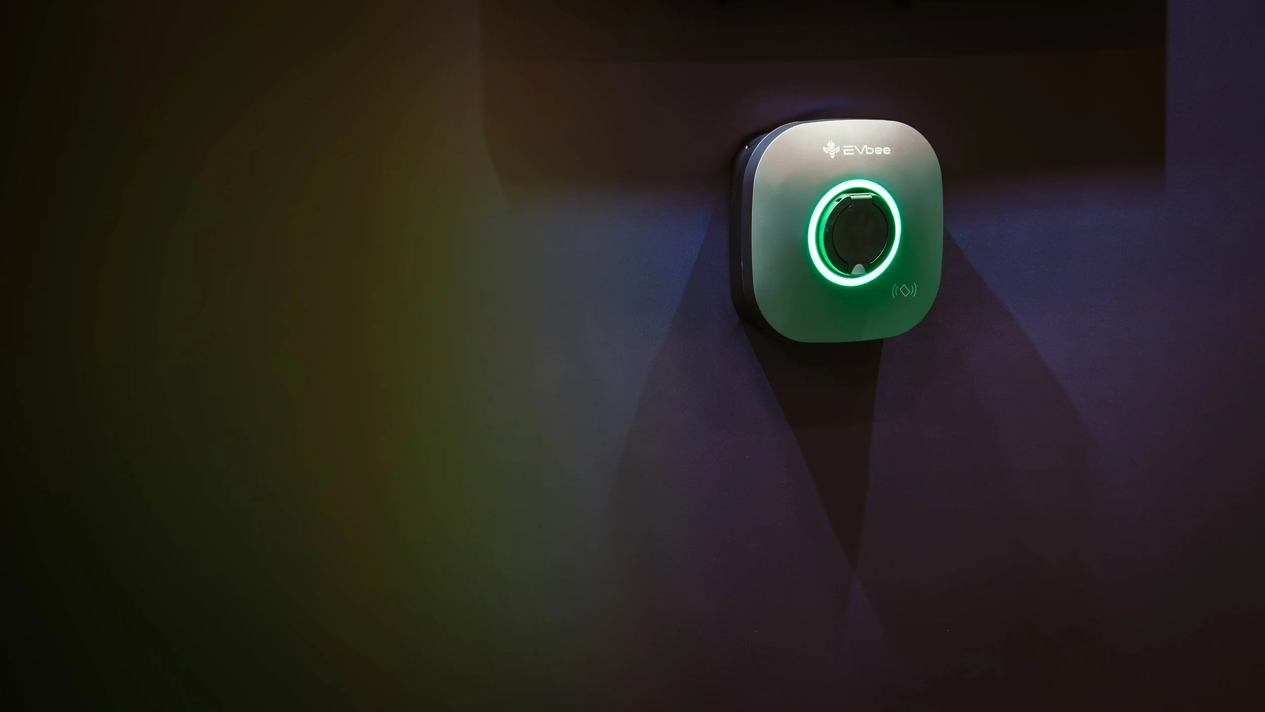 A wall-mounted device labeled 'EVbee' with a circular illuminated green ring around a central sensor or scanner.