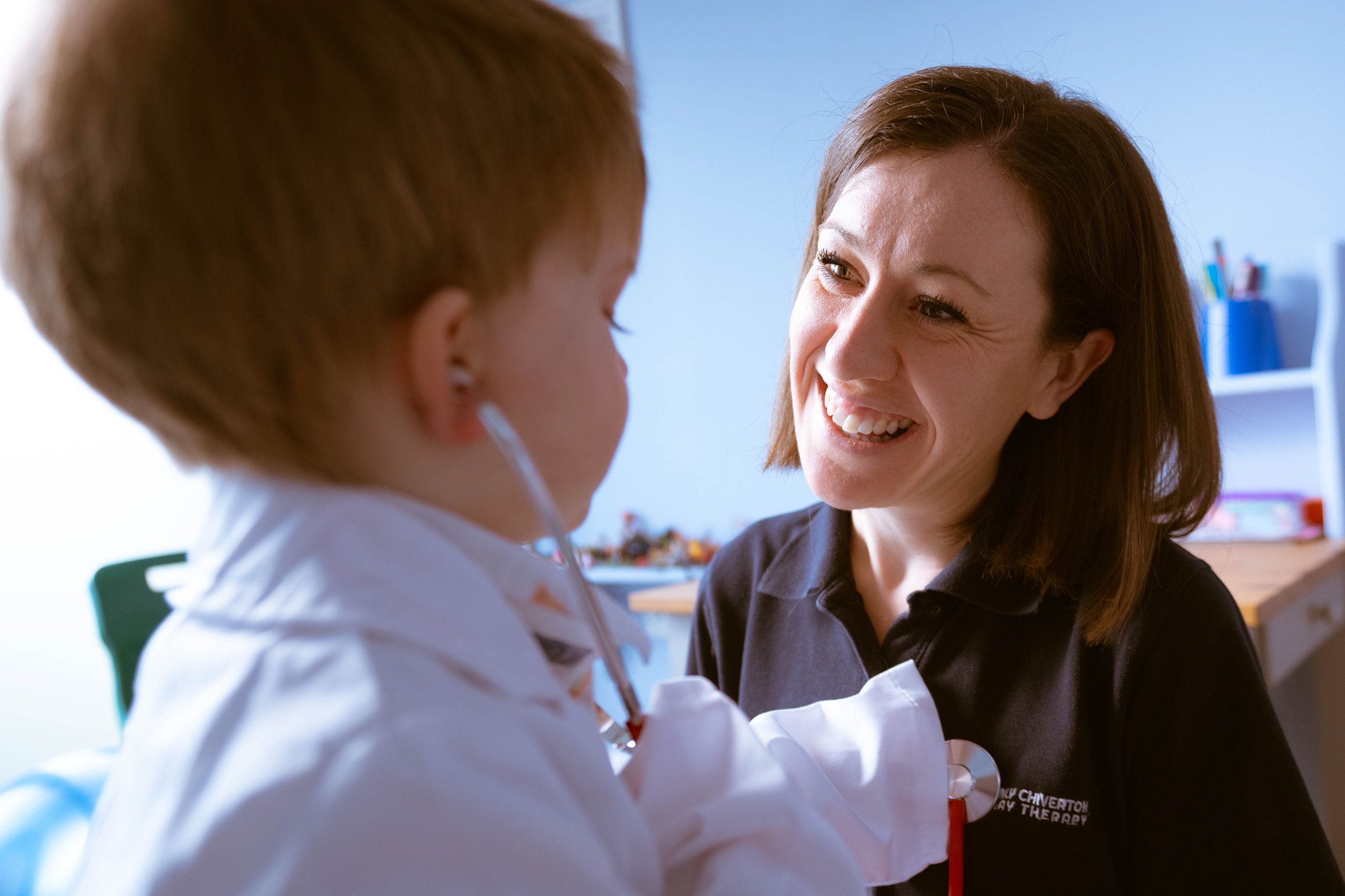 A woman smiling at a young patient in a healthcare setting.