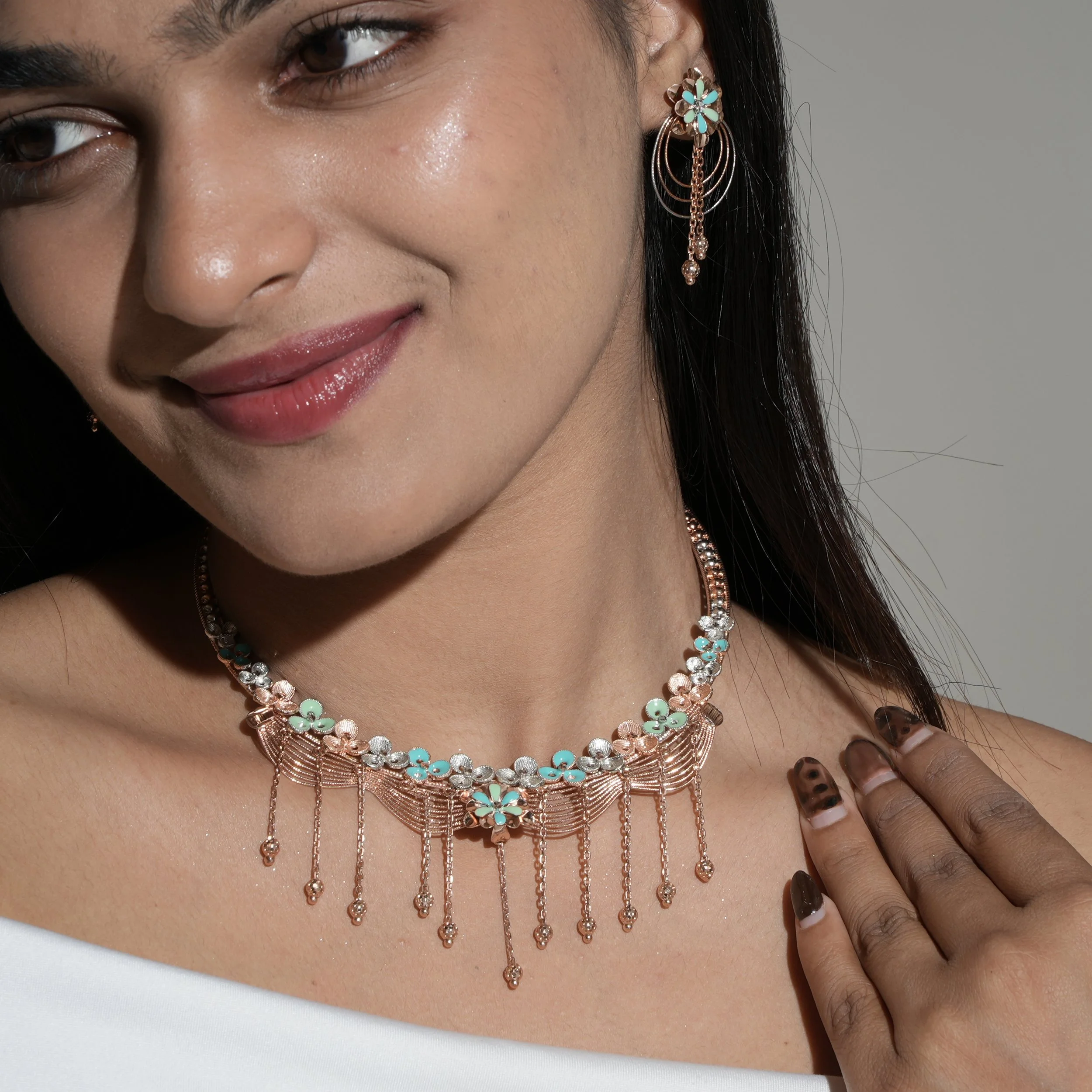 Close-up of a woman's smiling face showcasing turquoise and gold jewelry, including earrings, necklaces, and rings, with her hand touching her neck and leopard print nails.