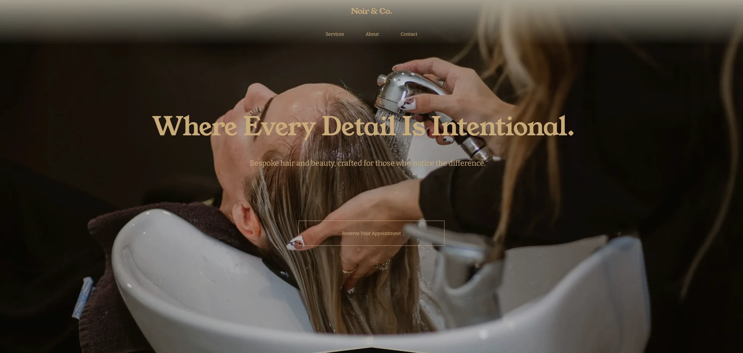 A woman is lying back in a hair salon sink with her head tilted back as a stylist washes her hair with water.
