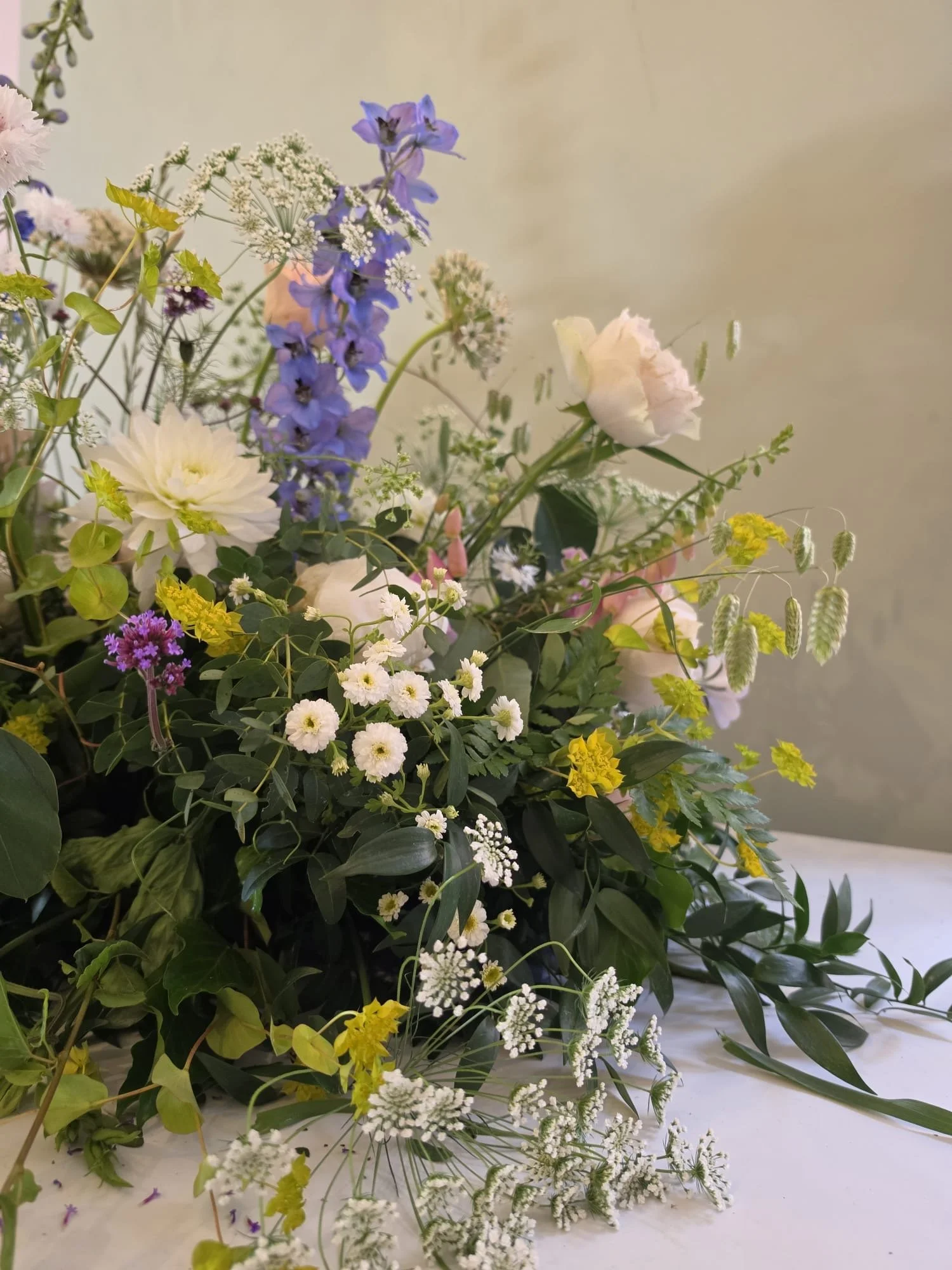 Joyful organic floral funeral arrangement in a church with purples, pinks white and greenery