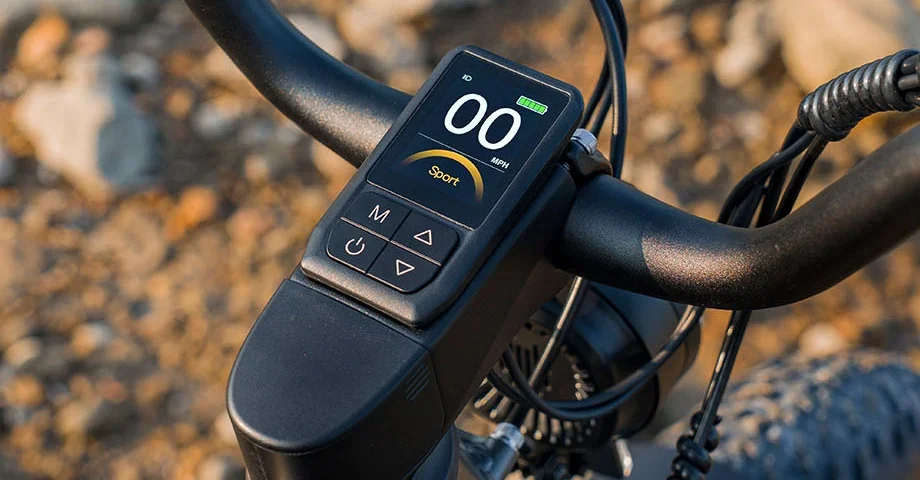 Close-up view of an electric bicycle's handlebar display showing a zero speed and battery indicator.
