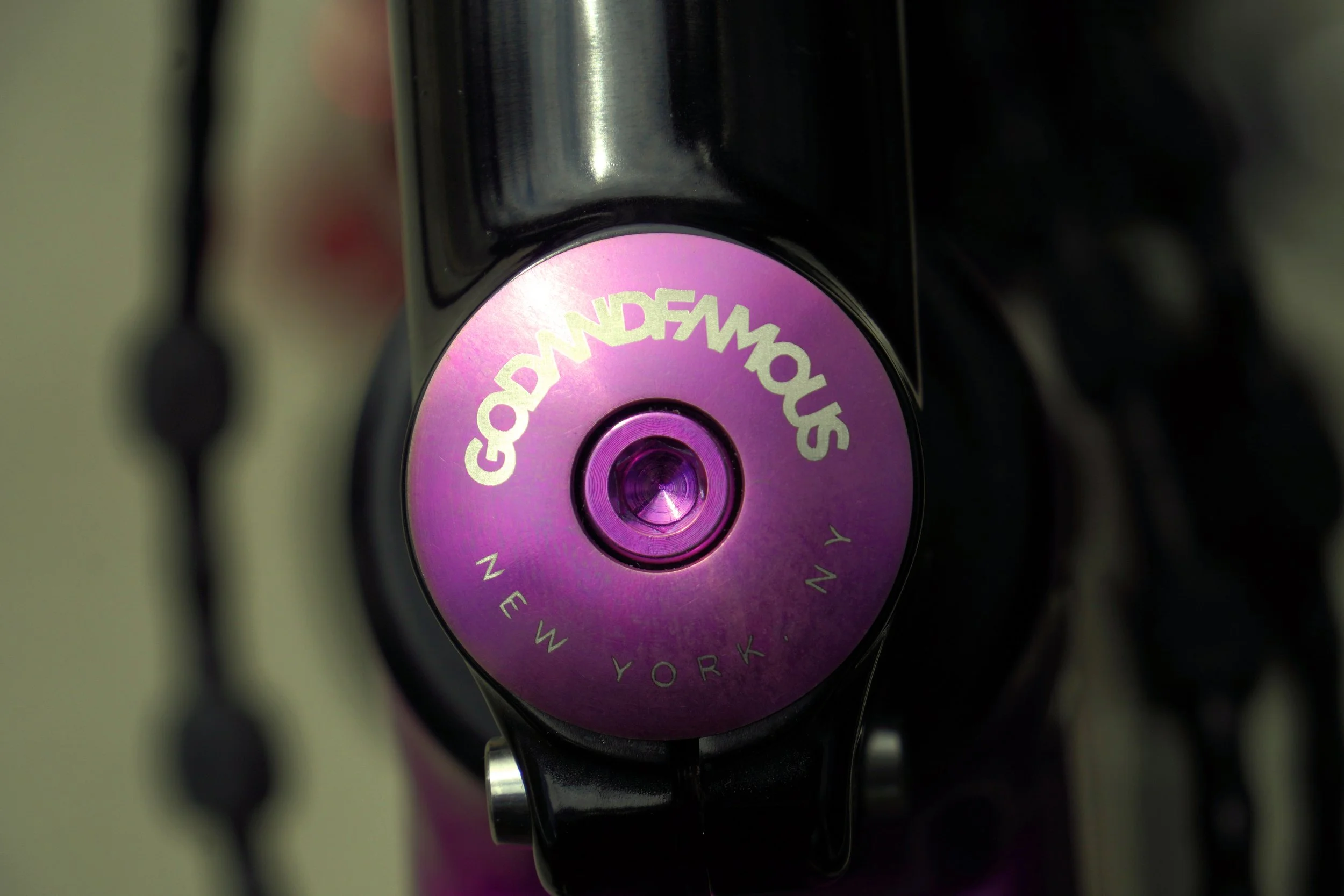 Close-up of a purple and black camera lens with the text The New York in a circular pattern around the center of the lens.