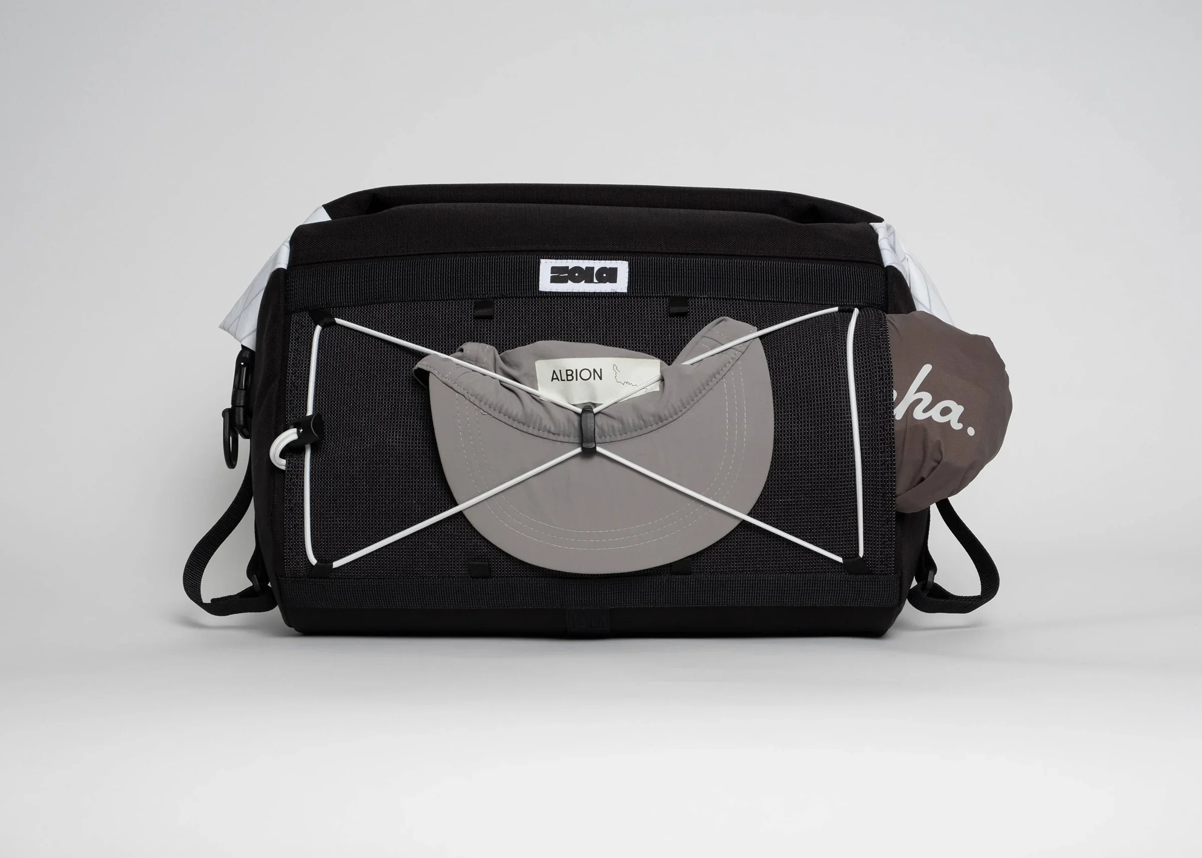 A black backpack with multiple compartments, white and gray accents, and a patch with the word 'ALBION' on the front. A gray hat with the word 'ALBION' is attached to the backpack with a white cord.