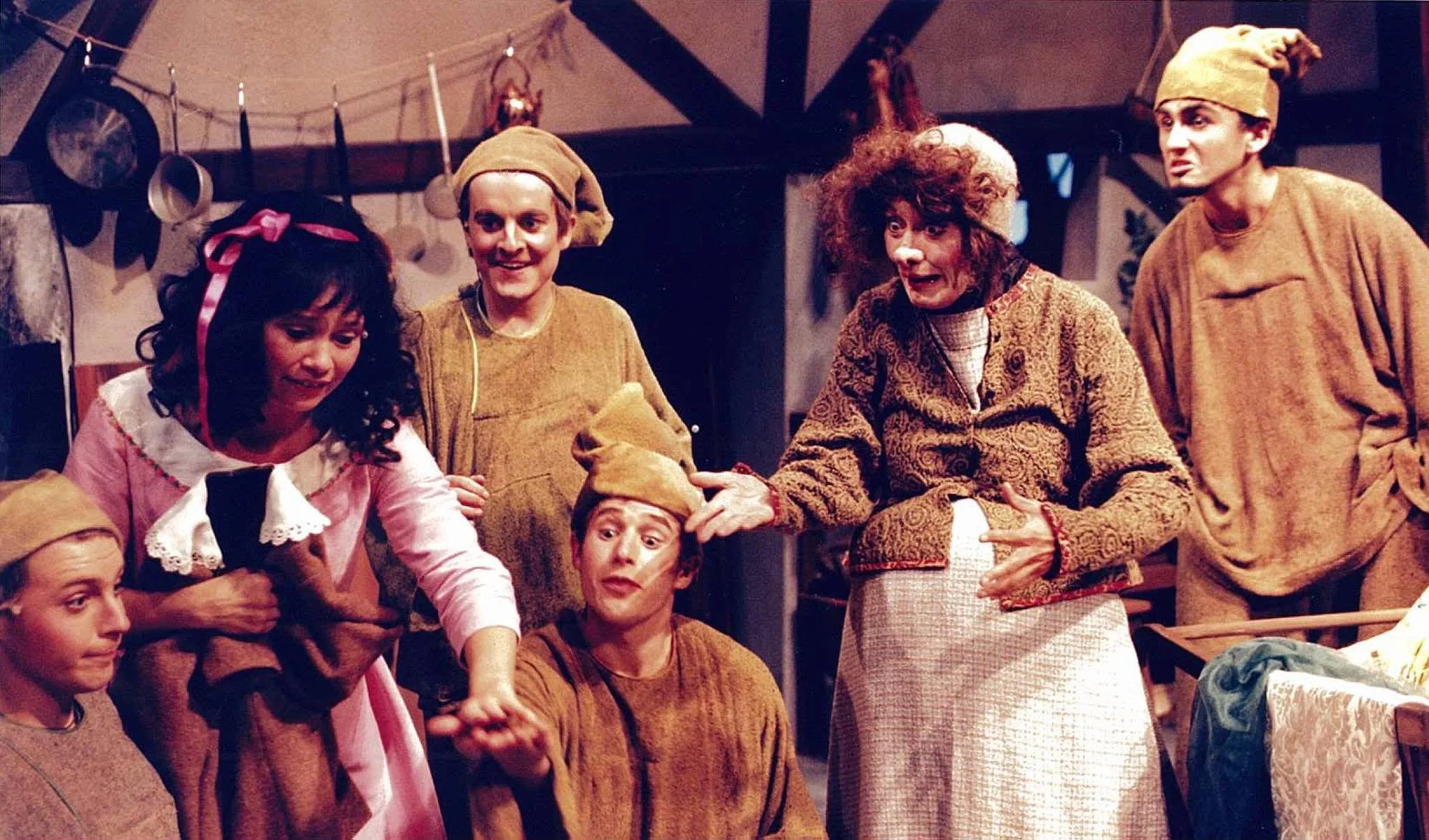 A scene from the movie 'The Wizard of Oz' showing characters Dorothy, the Scarecrow, the Cowardly Lion, and Tin Man in a cozy room, engaging in a lively interaction.