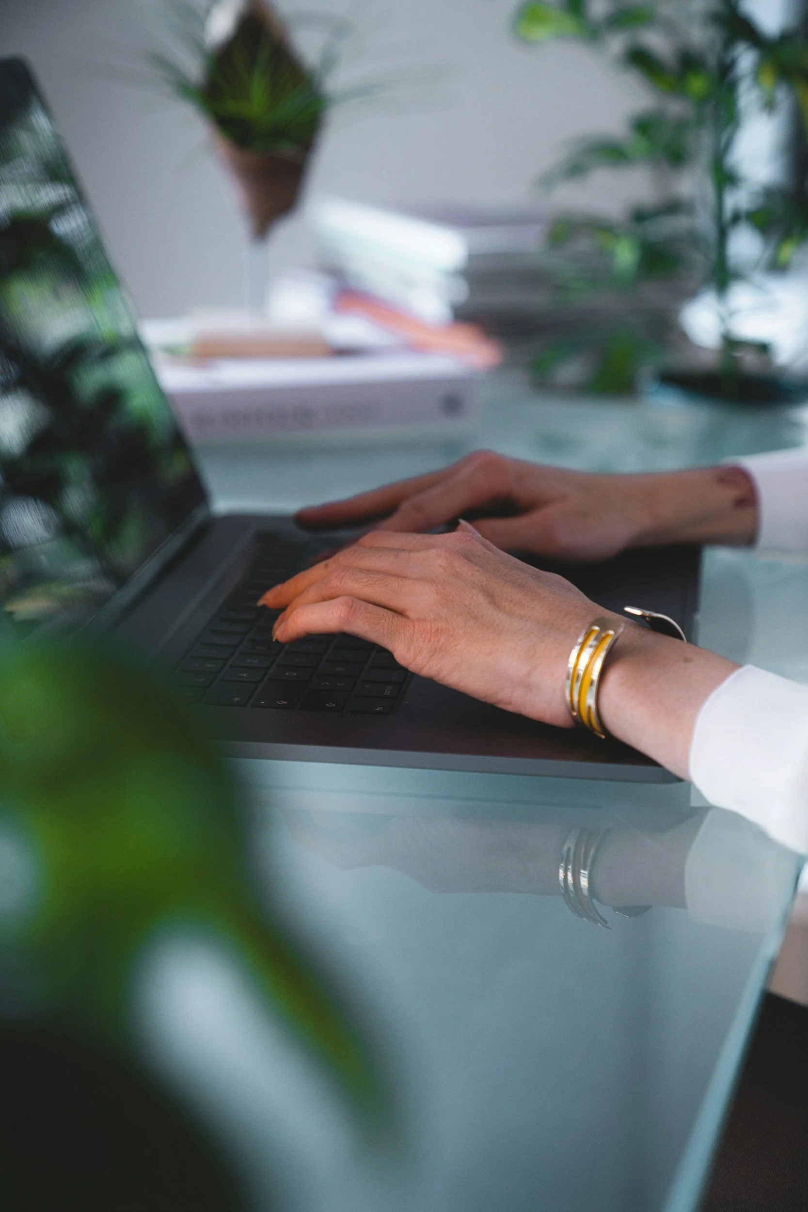 Close-up of a person working at a laptop in a calm, light-filled workspace, representing thoughtful communication and professional support.