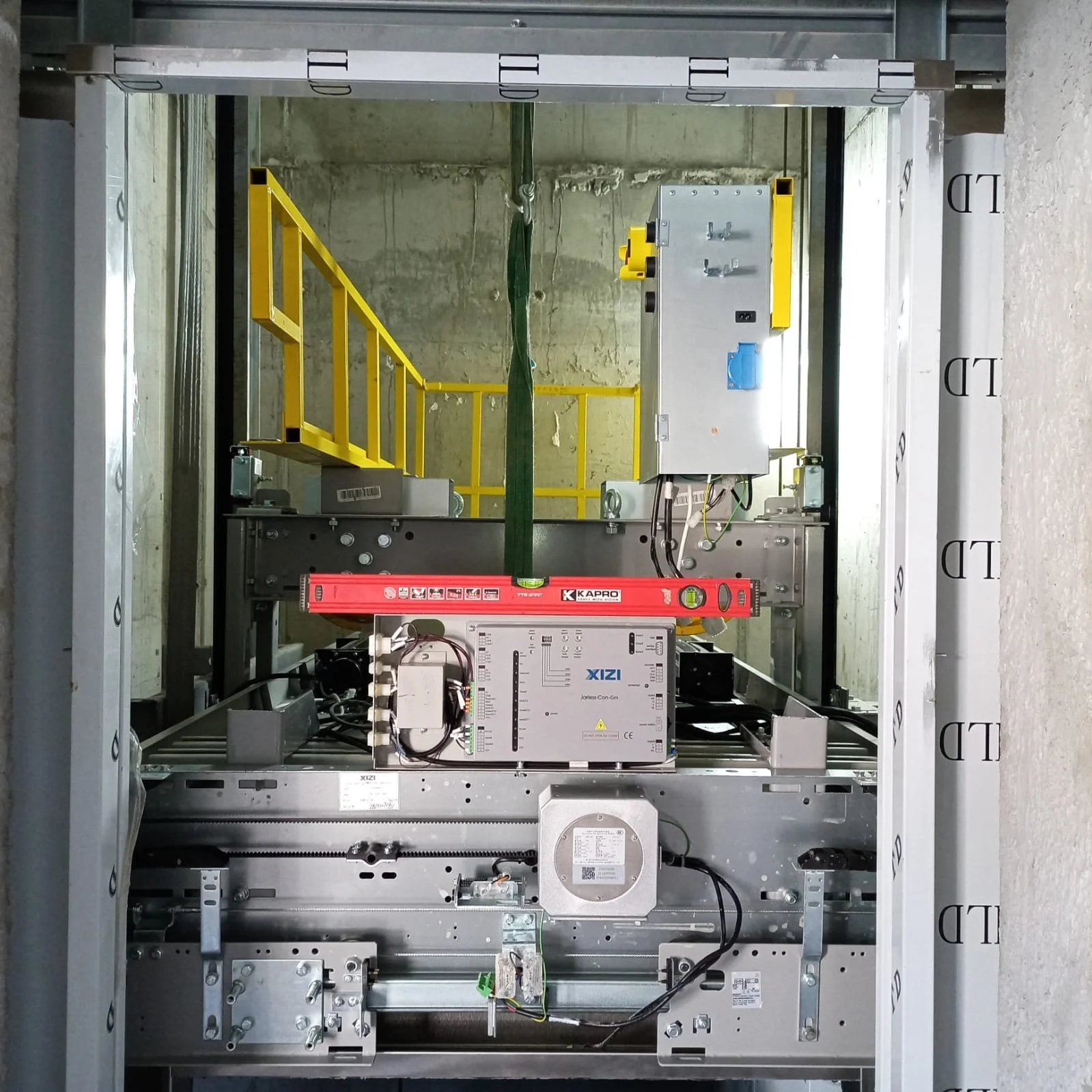 The image shows the inside of an industrial or control panel cabinet with various electronic components, wiring, and a yellow safety rail on the left side.