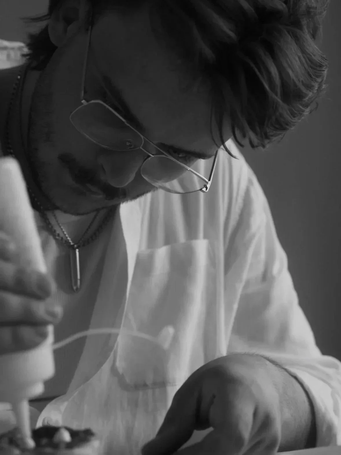 Schwarz-weiß-Foto eines Mannes mit Sonnenbrille, der sich auf eine Tätigkeit konzentriert.