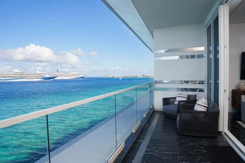Balcony view of the ocean with cruise ships and a partly cloudy sky, seen from a high-rise apartment