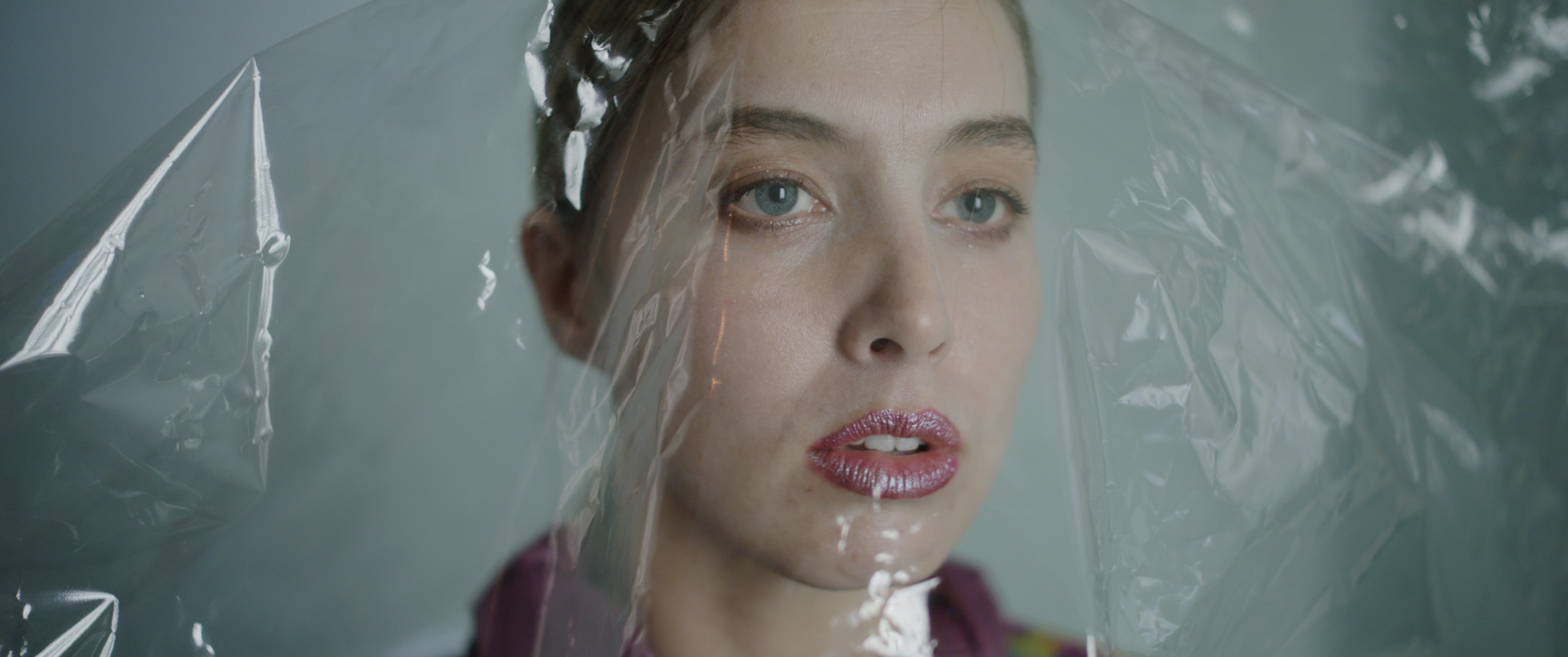 Close-up of a woman looking through a clear plastic sheet