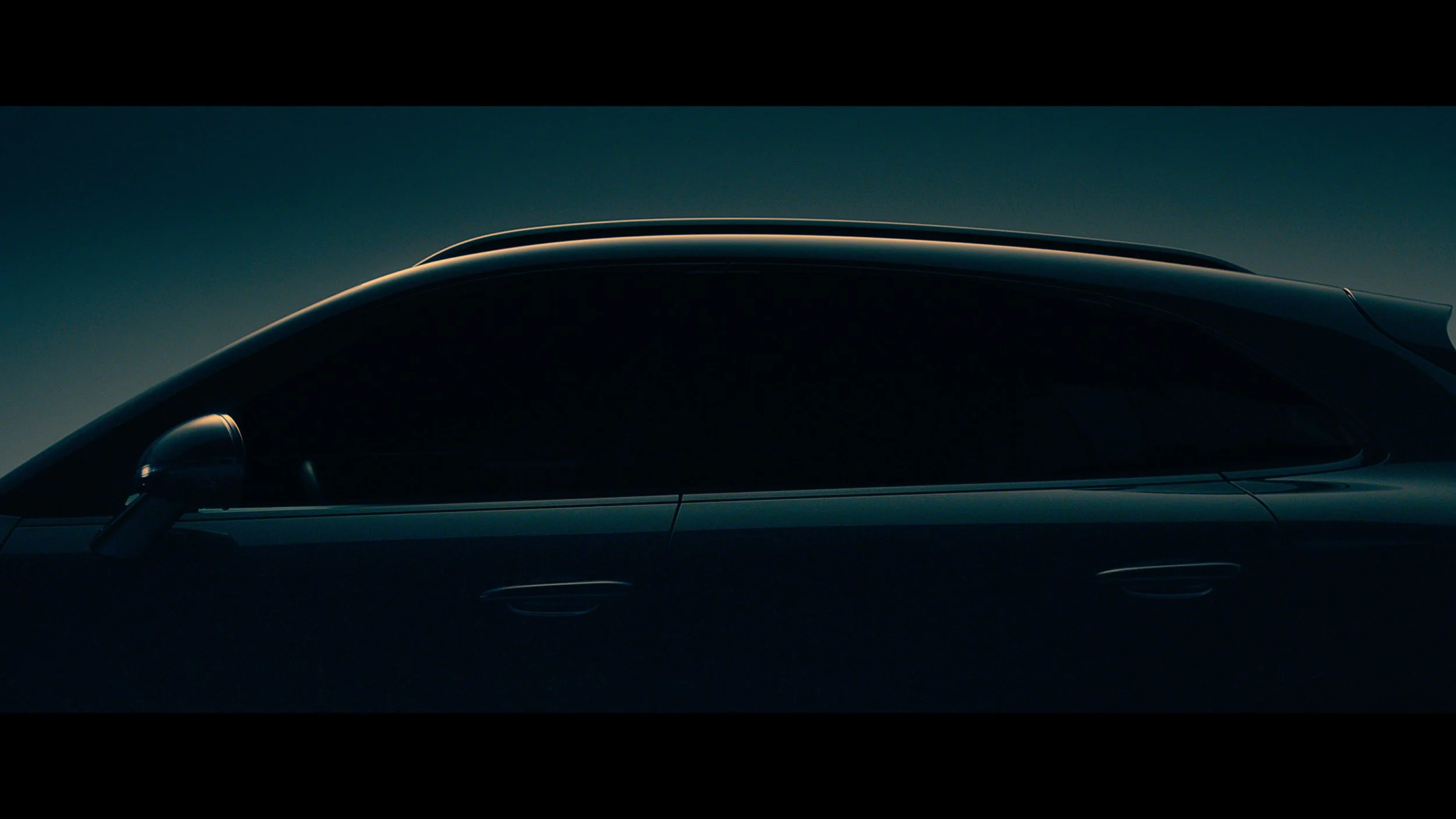 Close-up of a sleek, dark-colored sports car with a smooth, aerodynamic body, set against a dark background.