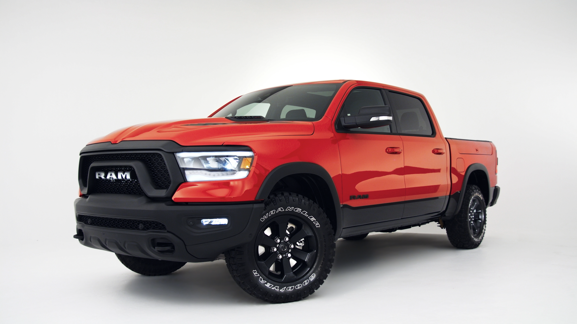 Red and black RAM pickup truck with off-road tires in a studio with a white background.