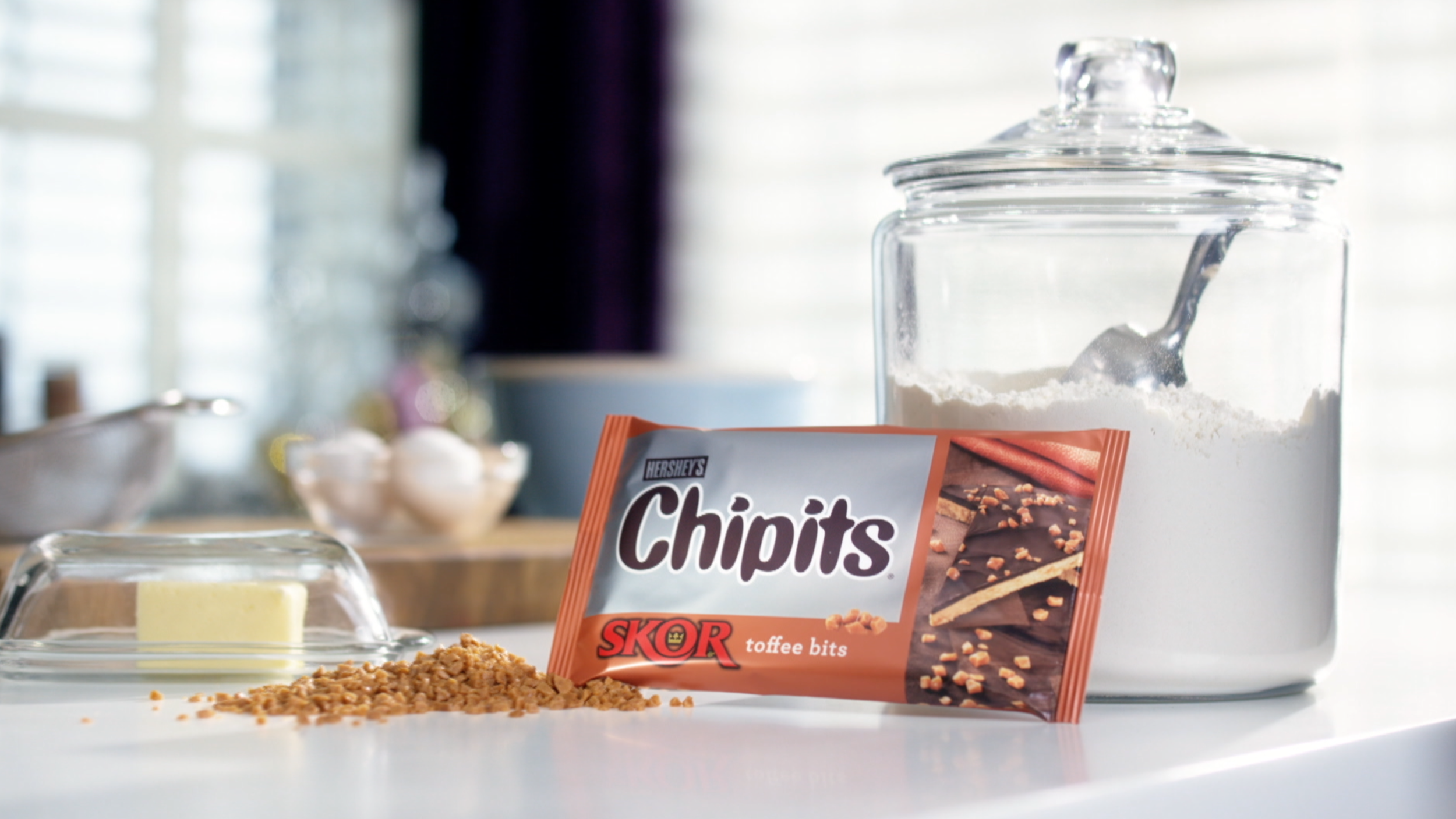 Hershey’s Chips toffee bits with a glass jar of sugar and baking ingredients.
